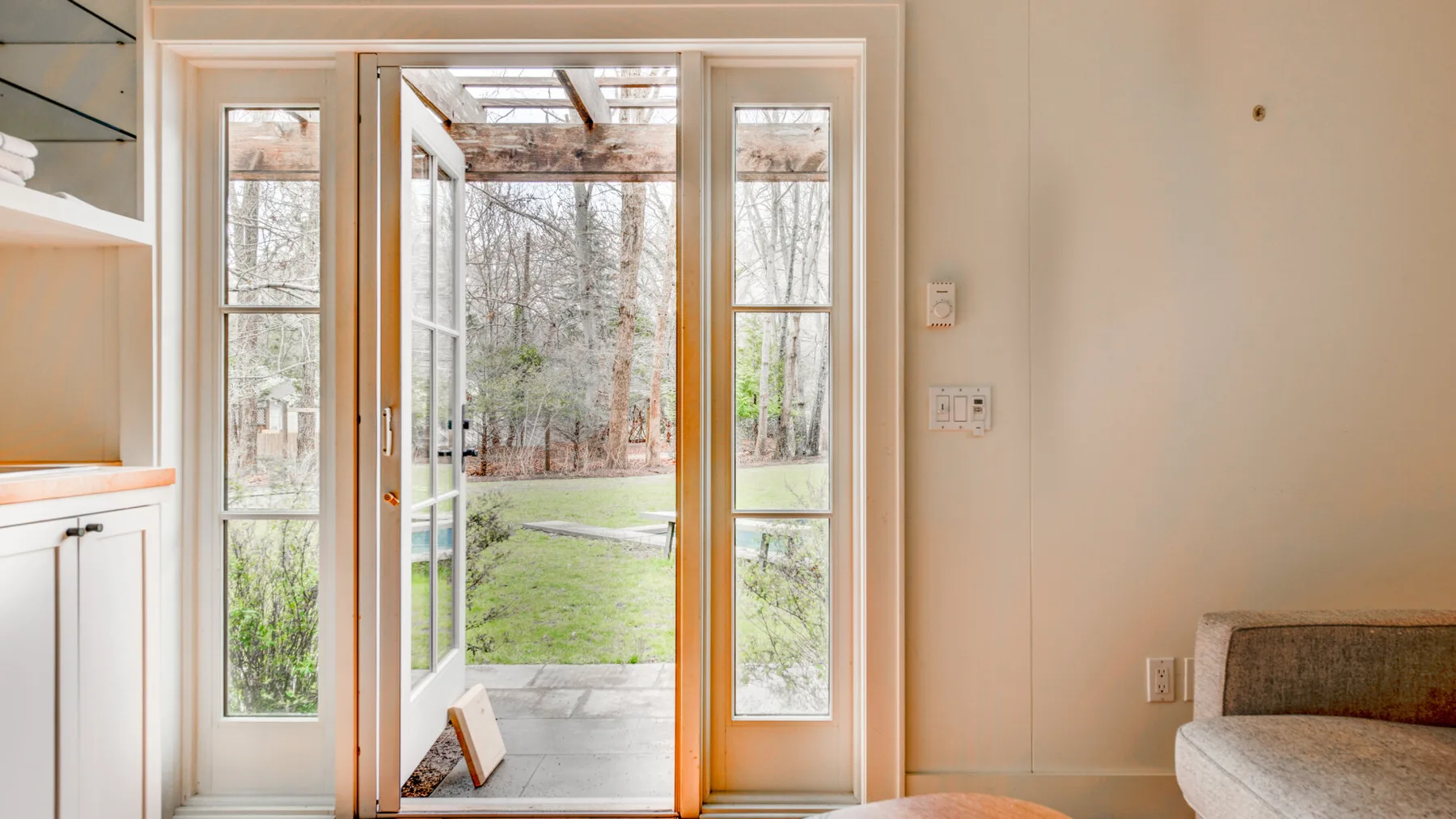 Una habitación luminosa da a un jardín a través de puertas de vidrio.