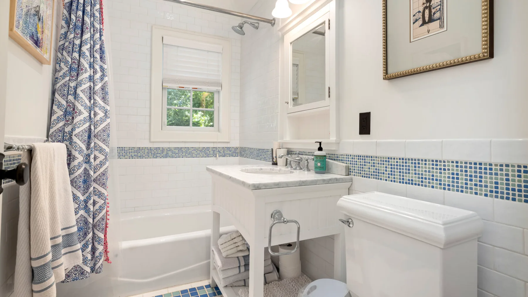 Un baño alicatado con bañera, lavabo y ventana.