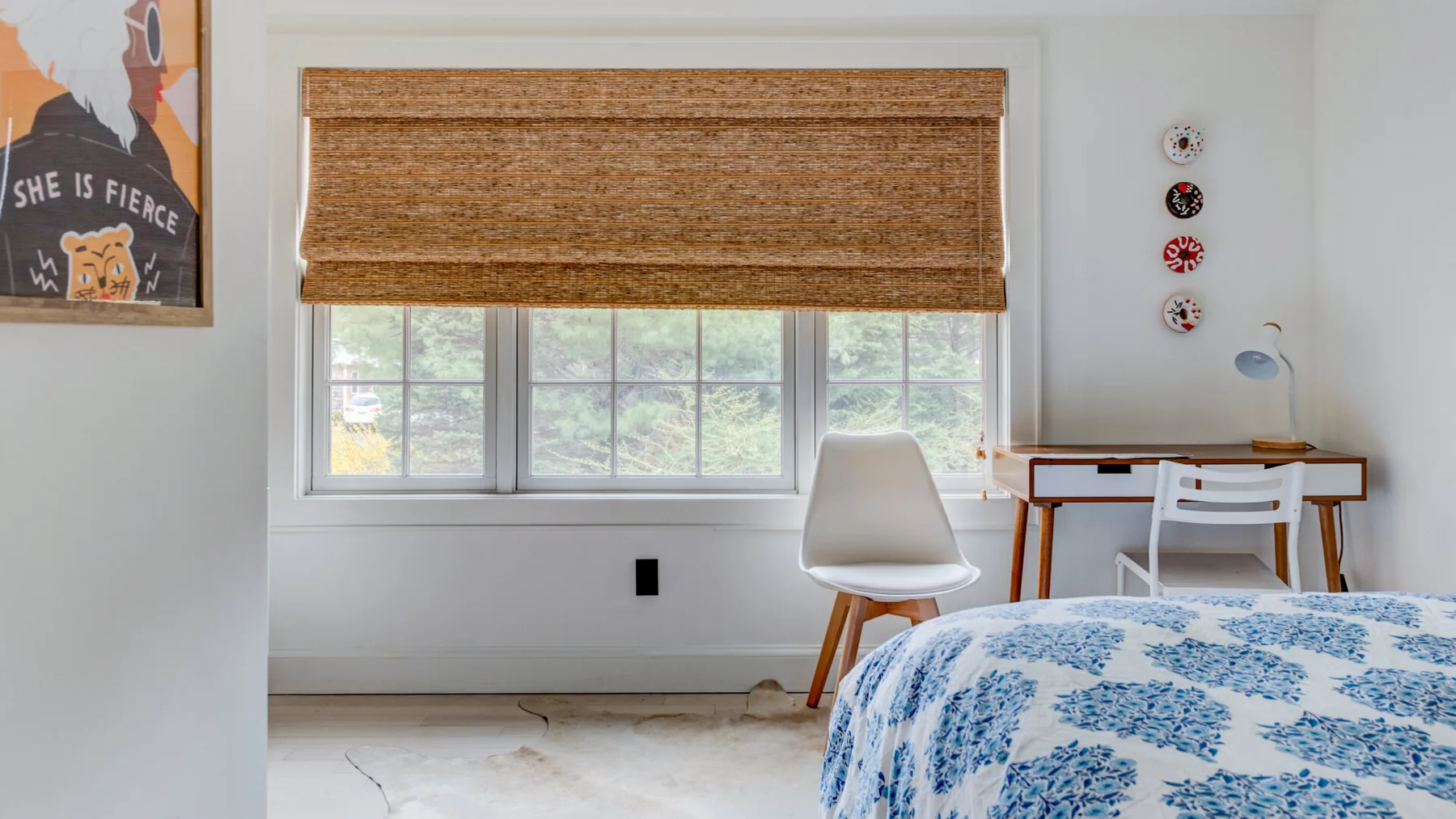 Un dormitorio luminoso con una cama cubierta de ropa de cama floral azul junto a una ventana.