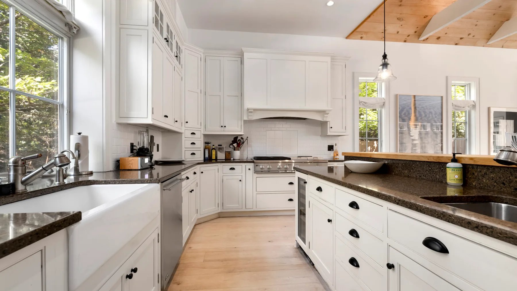 Una cocina luminosa con gabinetes blancos, encimeras oscuras y una isla central.