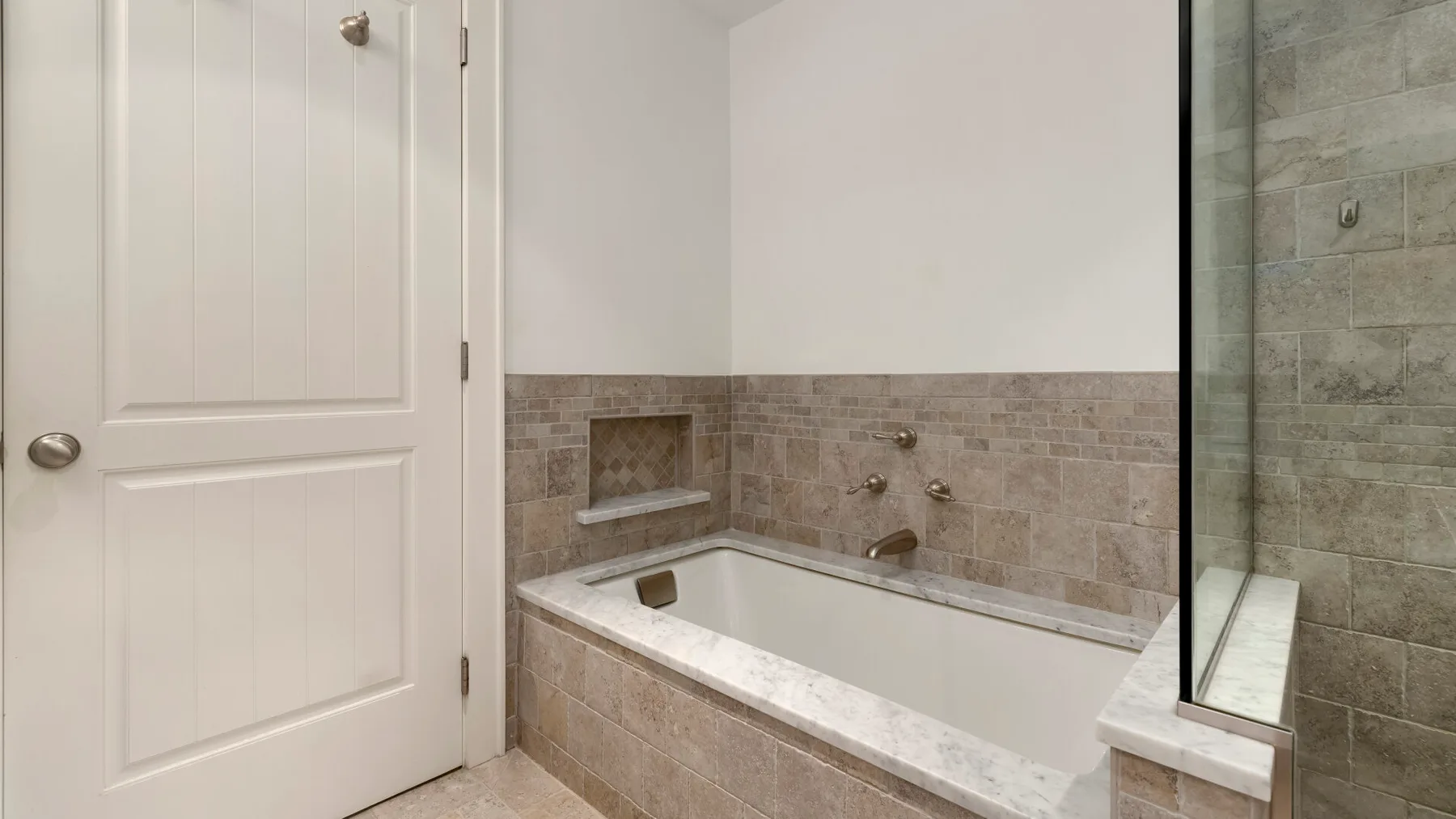 Un baño con una bañera empotrada y paredes revestidas de azulejos.