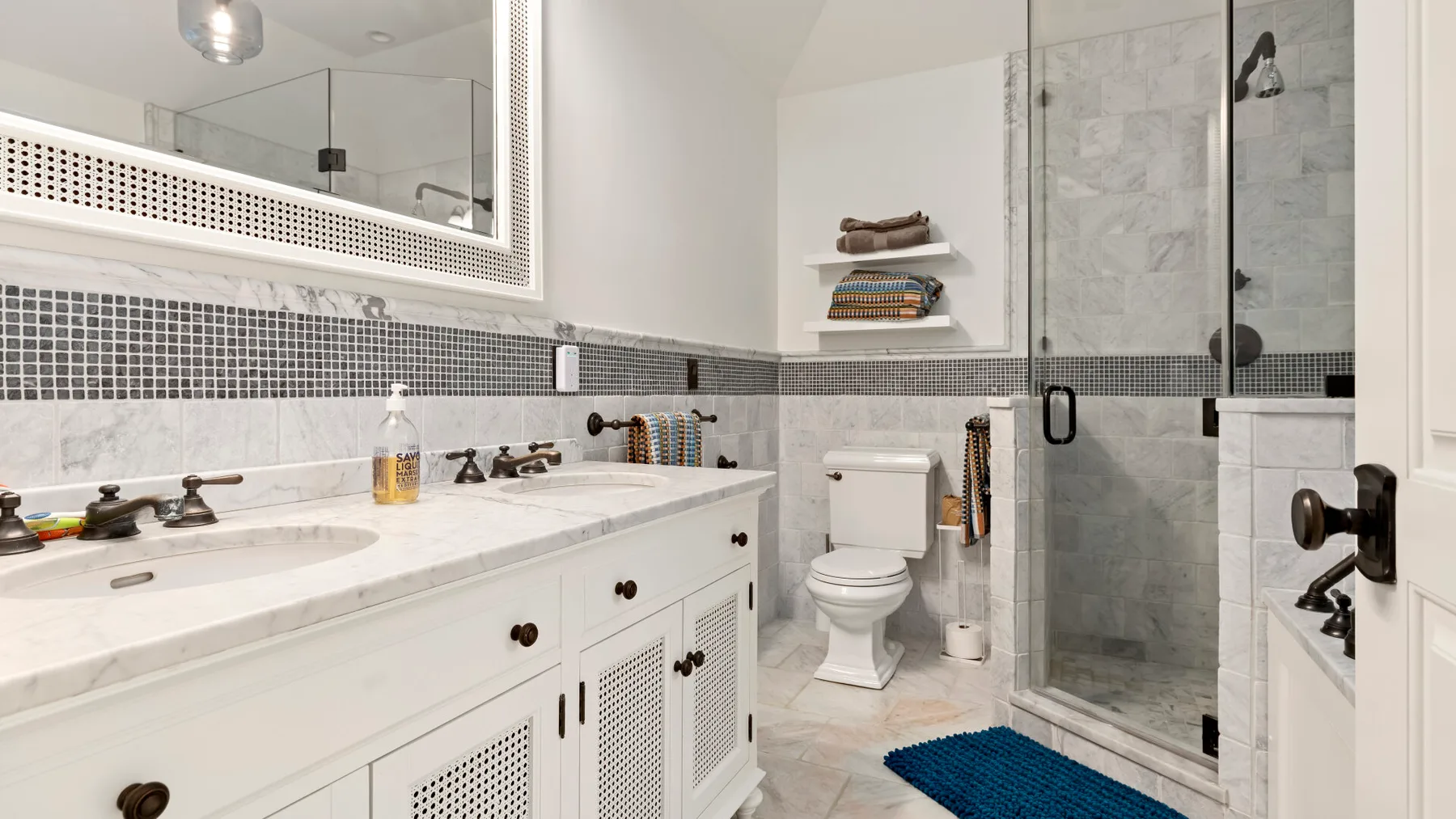 Un baño luminoso con lavabo, inodoro y ducha de vidrio.