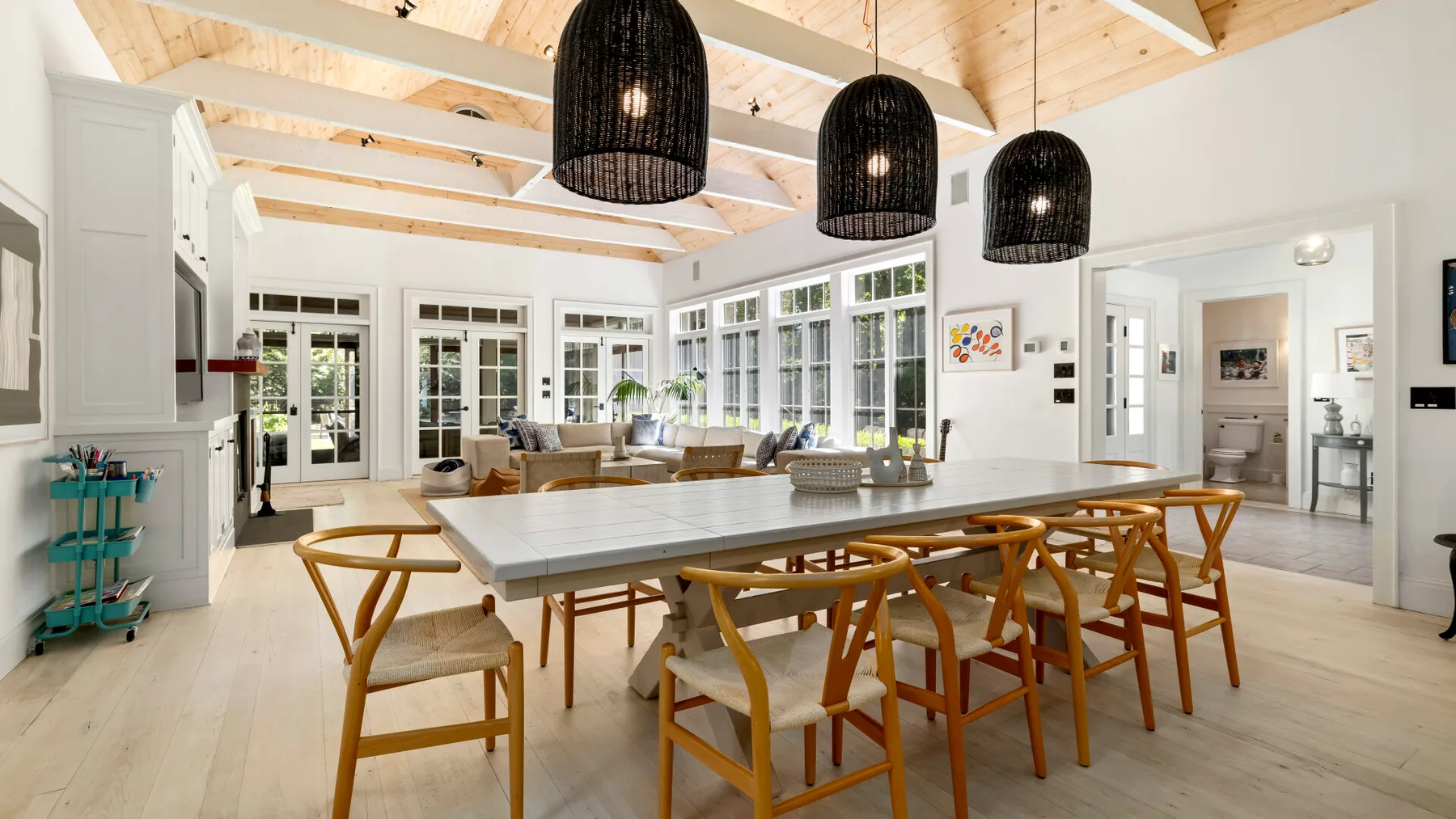 Un comedor luminoso con una mesa larga y lámparas colgantes tejidas.