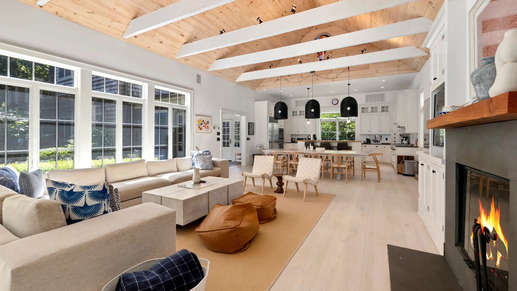 Una luminosa sala de estar y comedor de planta abierta tiene grandes ventanas y una chimenea.