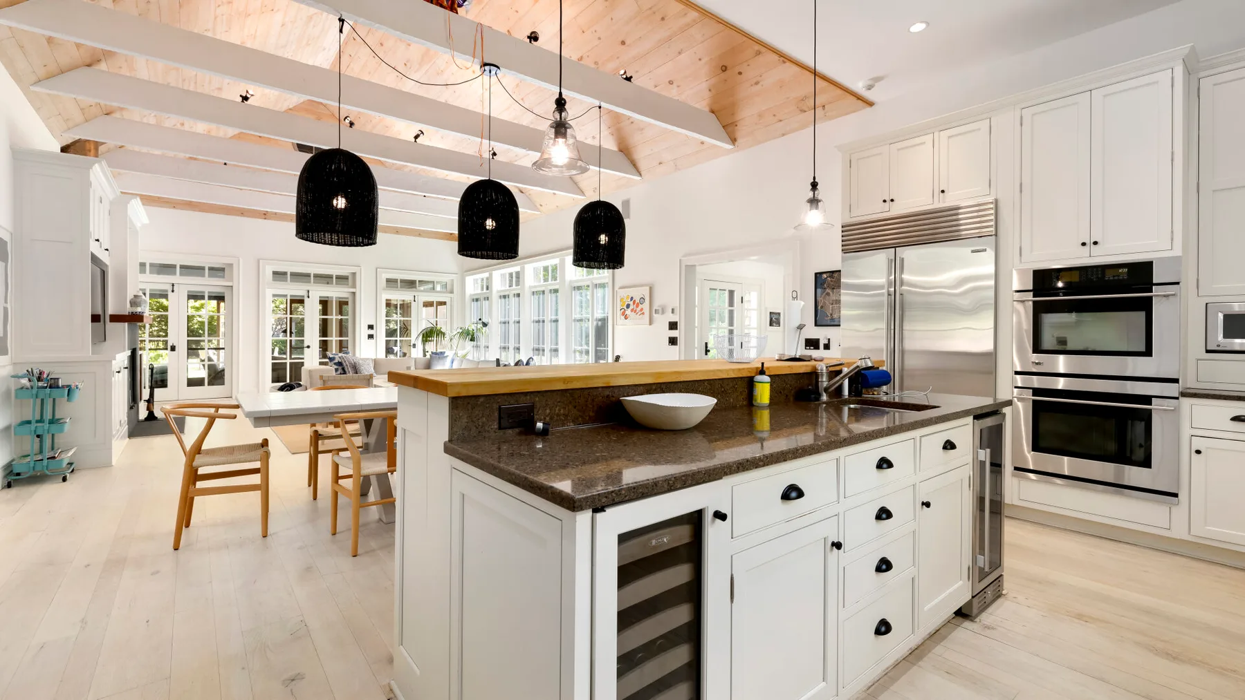 Una cocina luminosa con una isla grande, gabinetes blancos y luces colgantes.