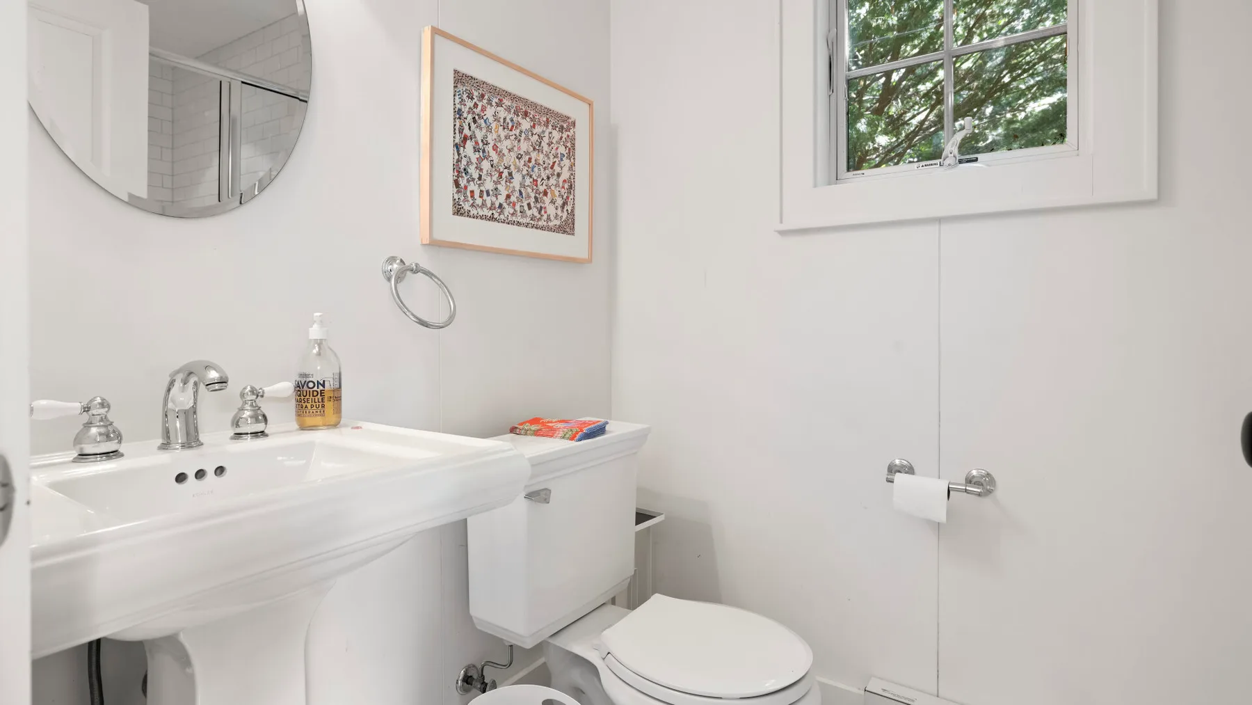 Un baño luminoso con lavabo, inodoro y ventana.