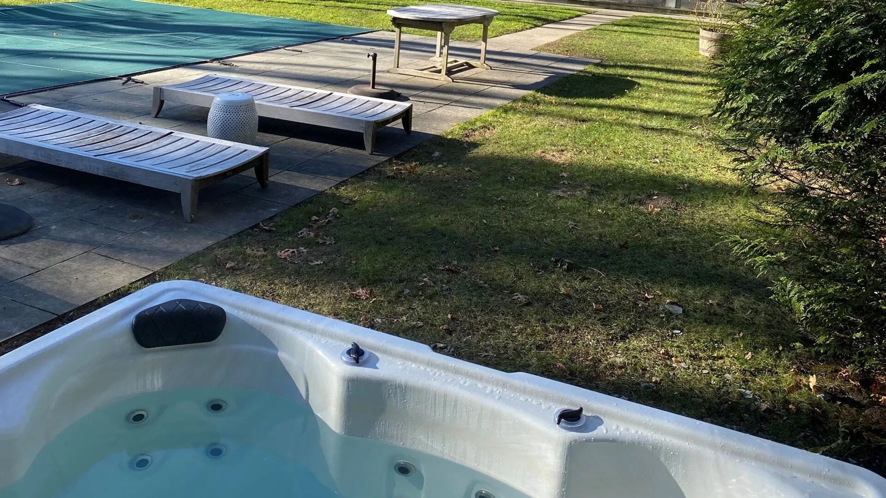 Un jacuzzi al aire libre está junto a una piscina y tumbonas.