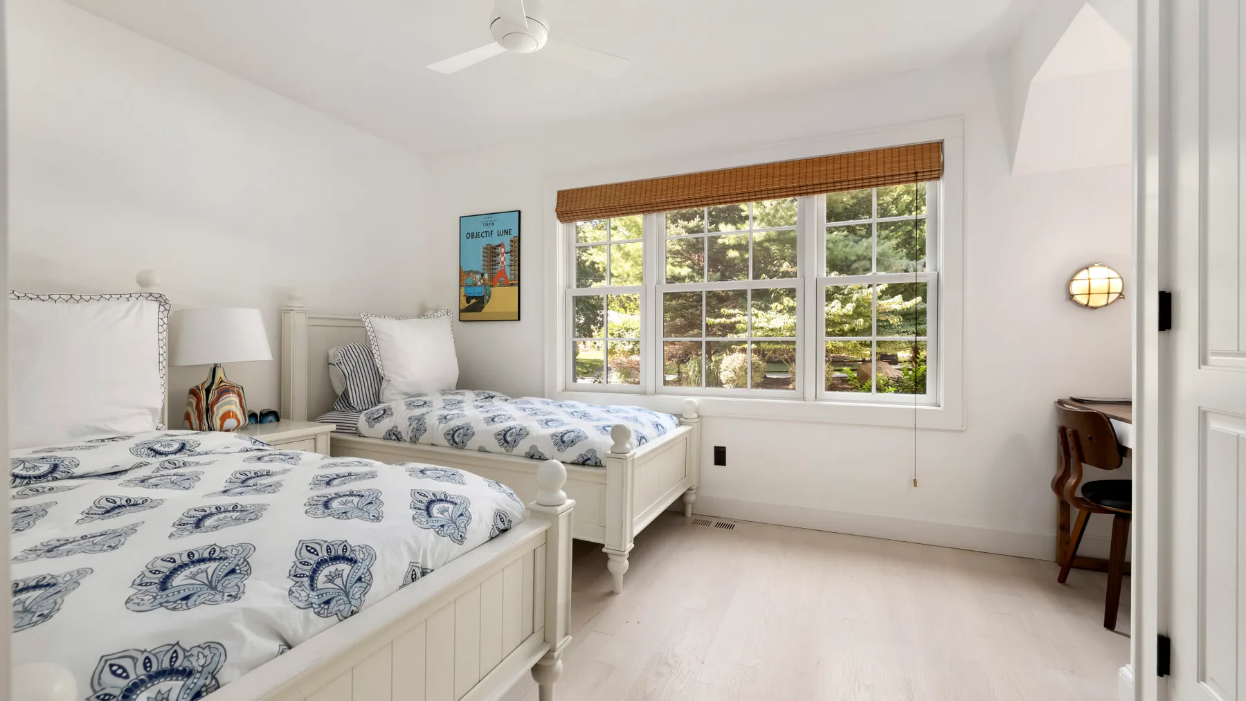 Un dormitorio luminoso con dos camas y una ventana grande con vistas a la vegetación.