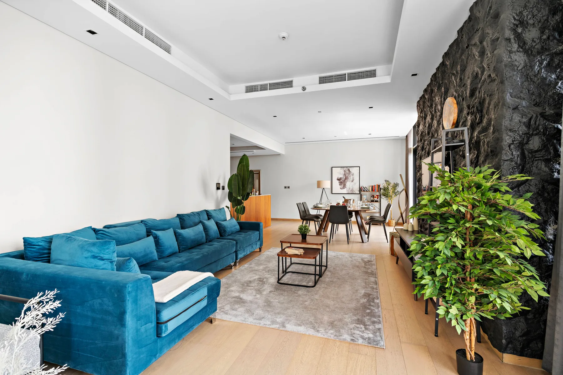 A bright living room with blue seating, a coffee table, and plants.