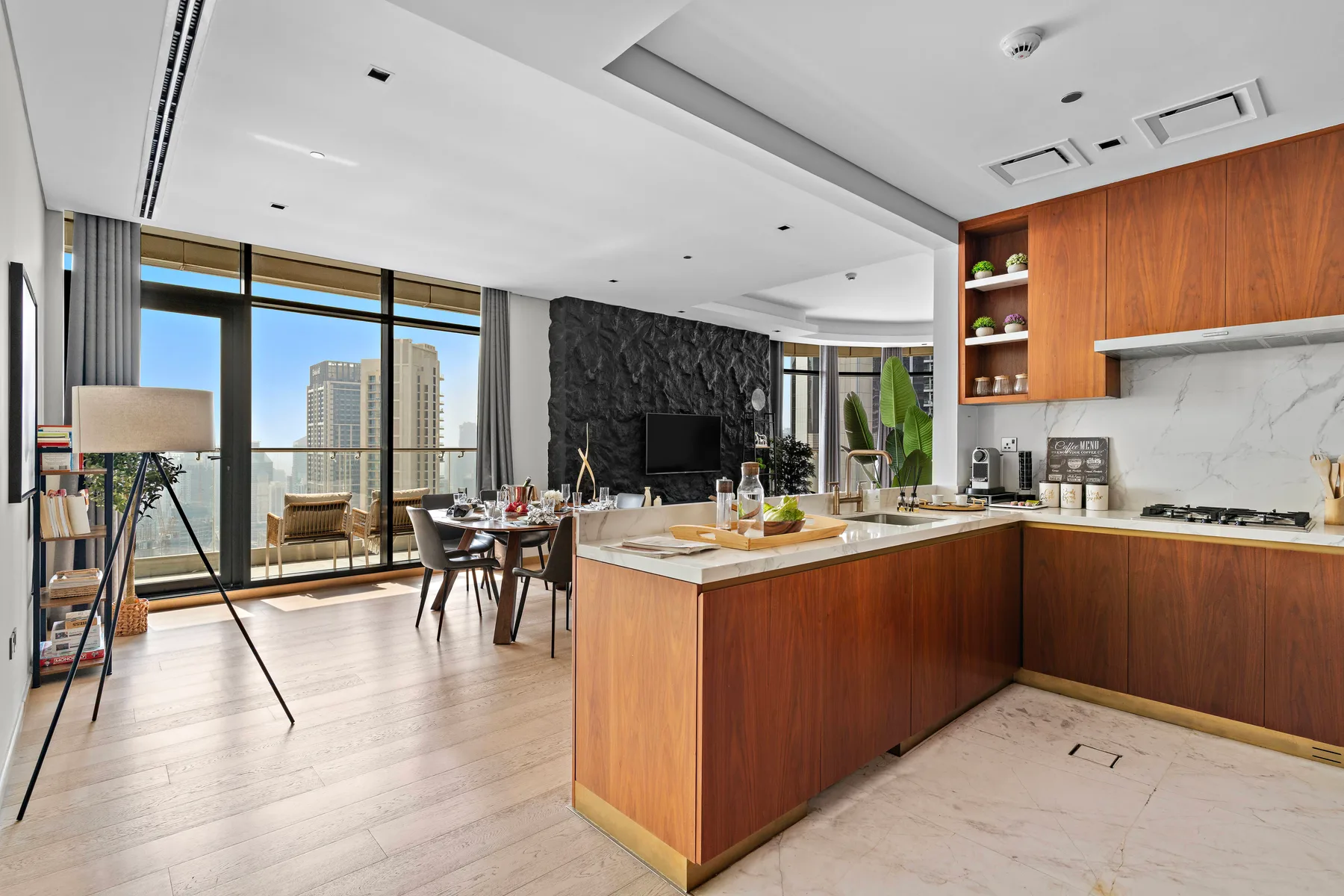A modern kitchen opens onto a dining area with floor-to-ceiling windows.
