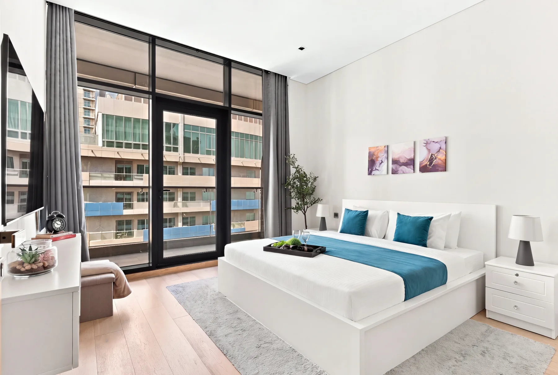 A bright bedroom with a white bed and floor-to-ceiling windows.