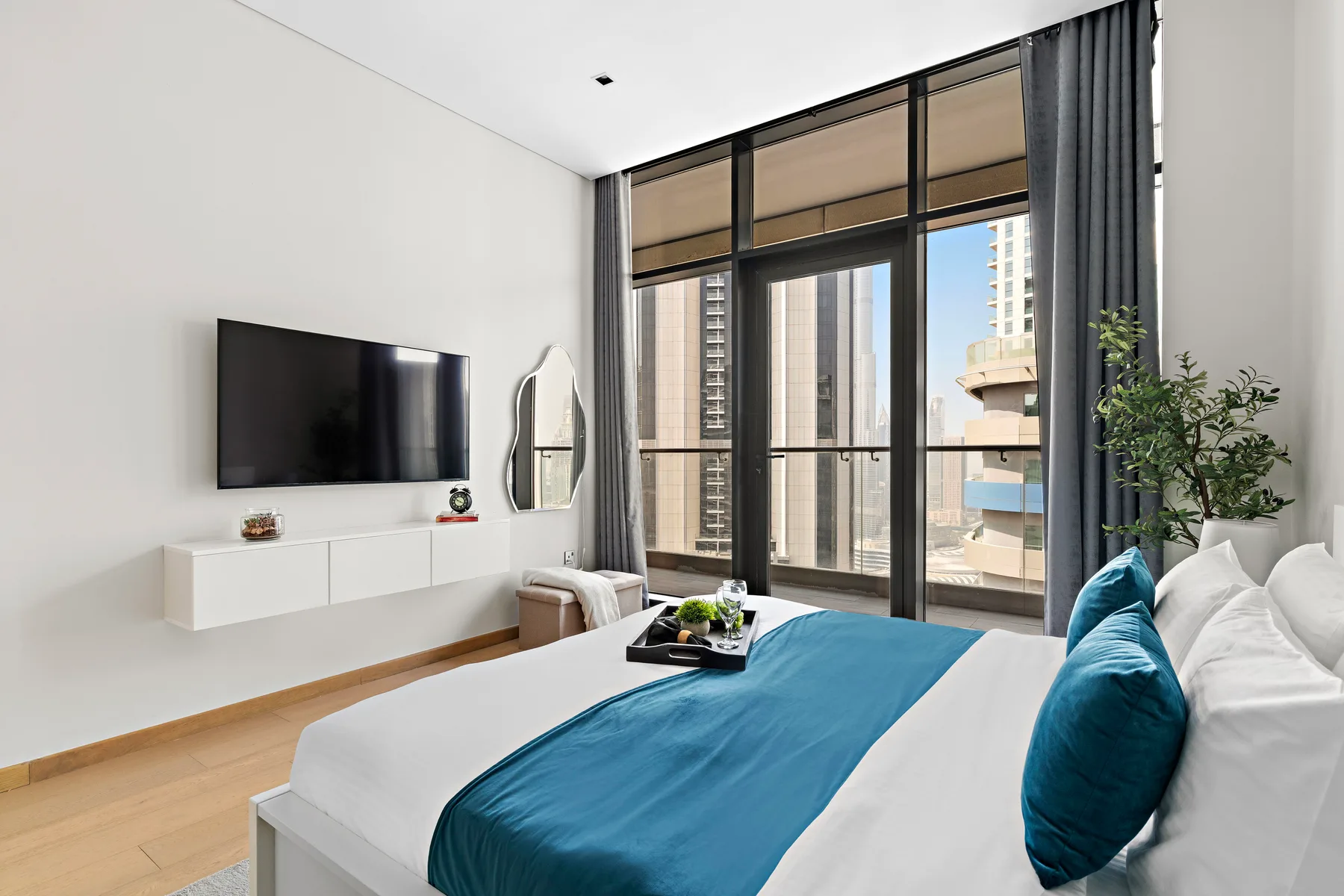 A bright bedroom with a bed and large floor-to-ceiling windows.