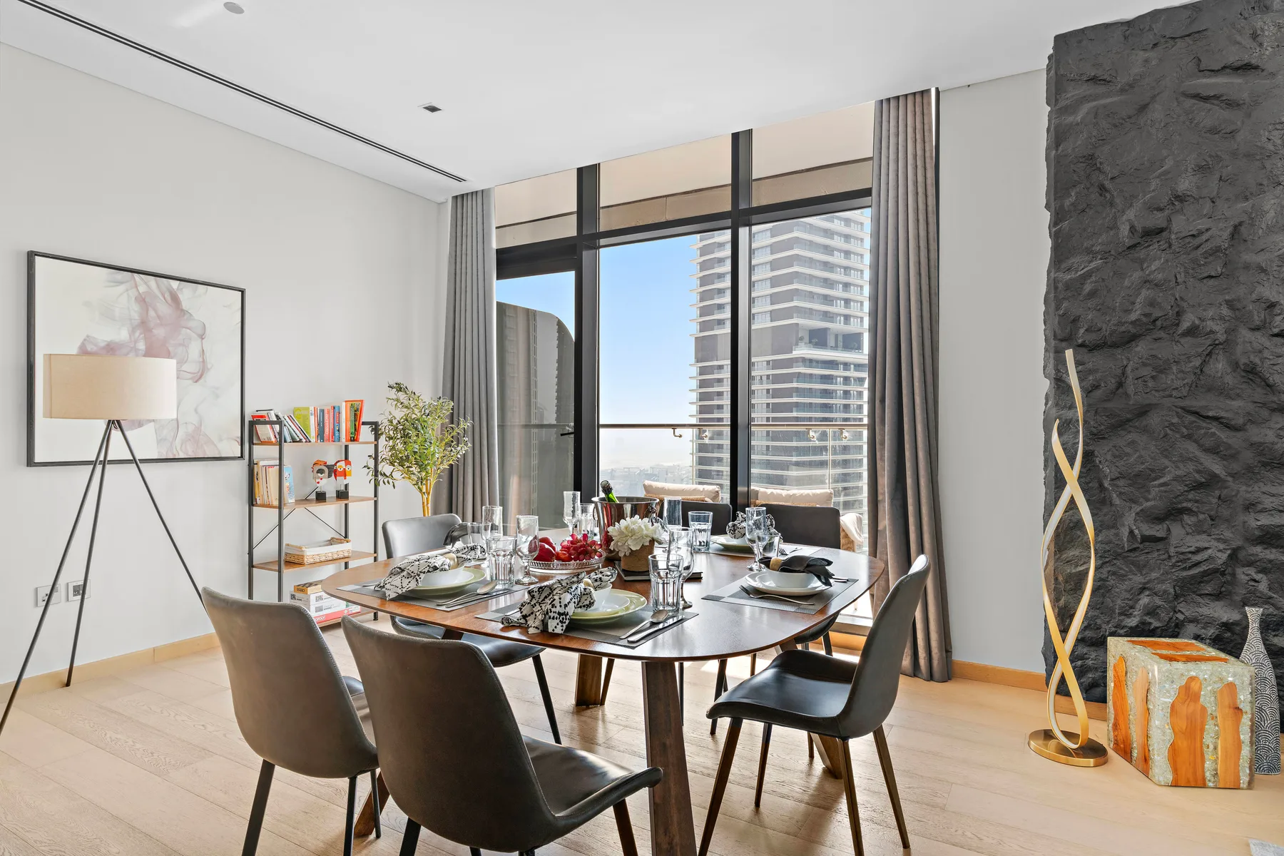 A dining area with a set table beside large windows.