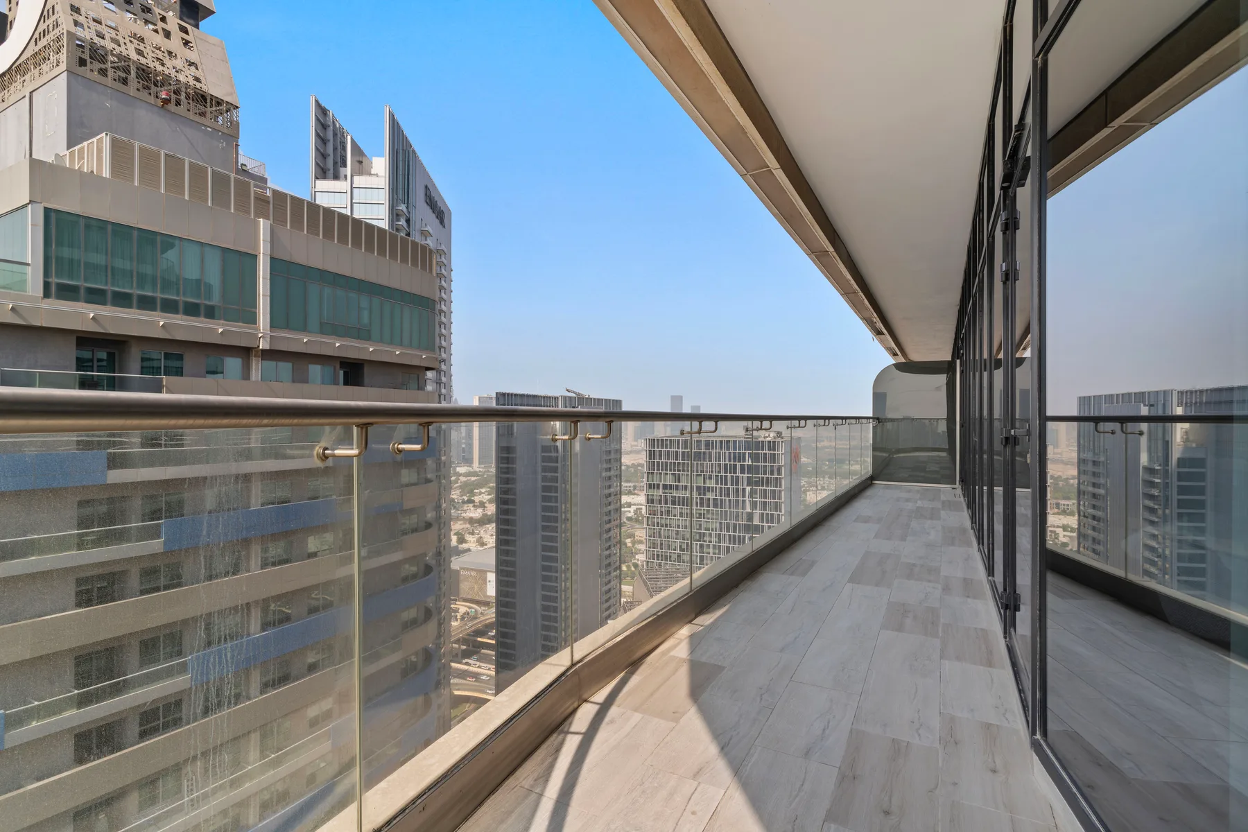 A balcony with glass railing overlooks nearby high-rise buildings.