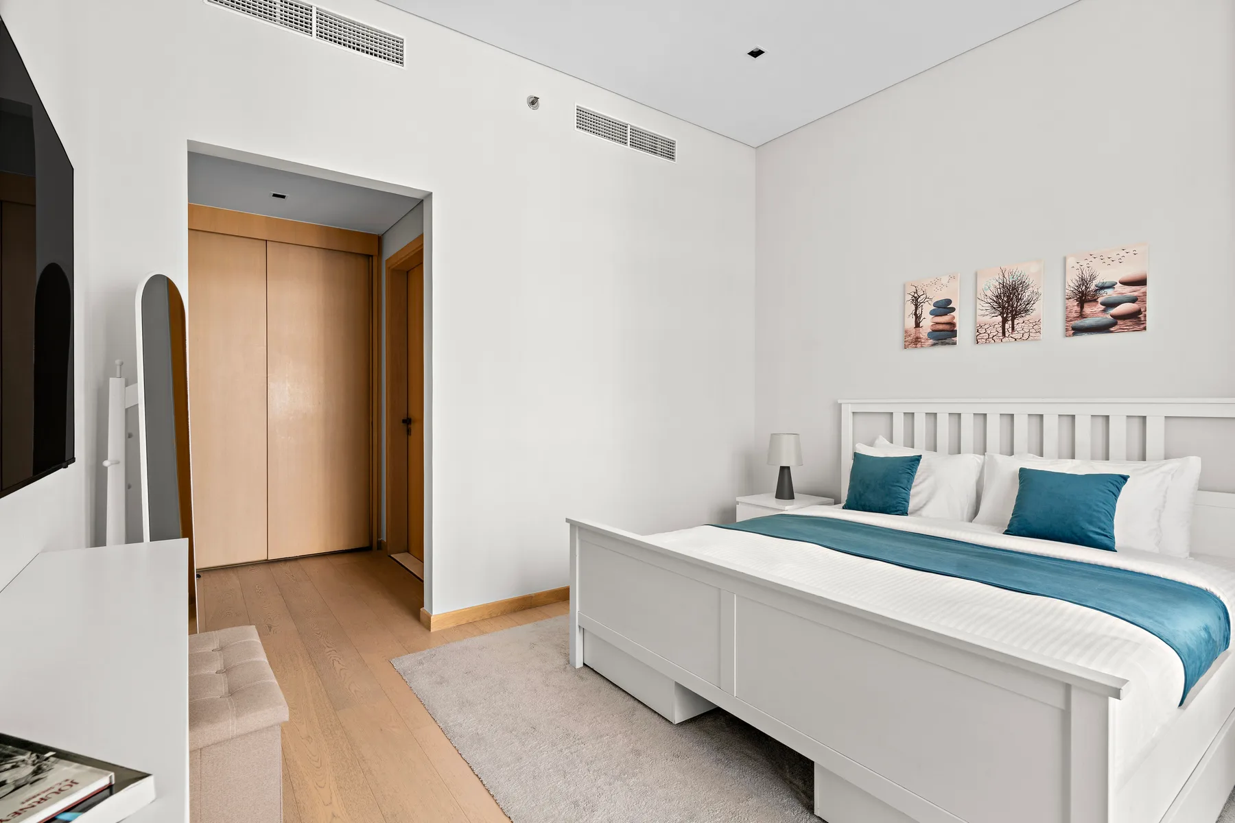 A bright bedroom with a white bed and blue bedding.