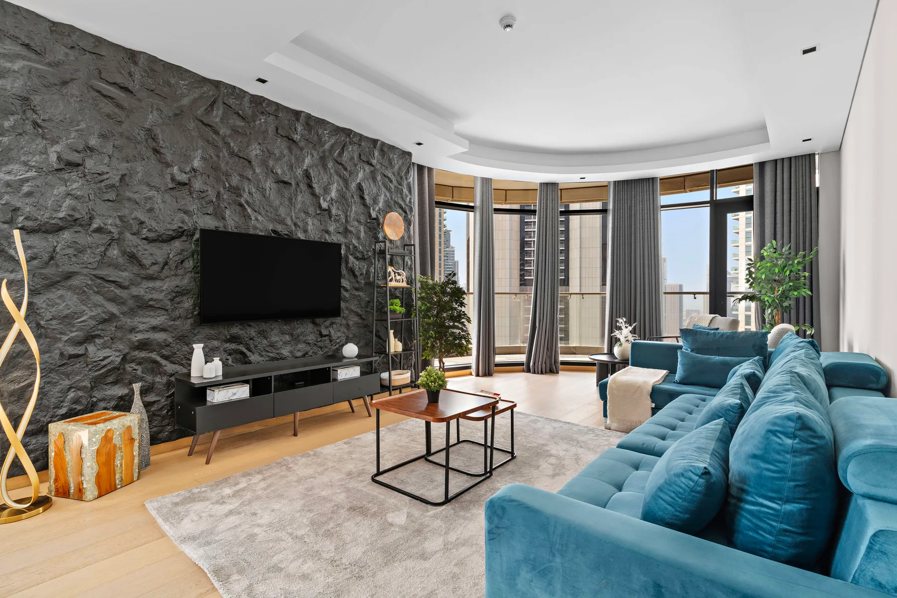 A modern living room with blue seating, a television, and large windows.
