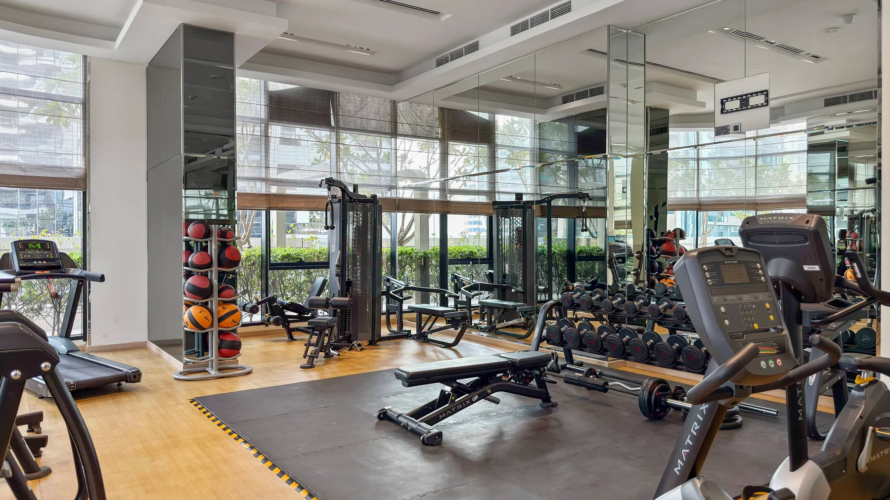 A gym with exercise machines, weights, and floor-to-ceiling windows.