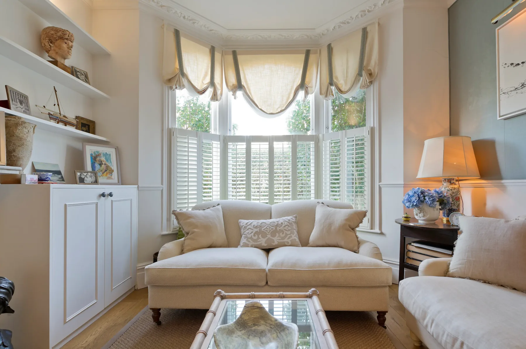 A bright living room with a sofa beneath a bay window.