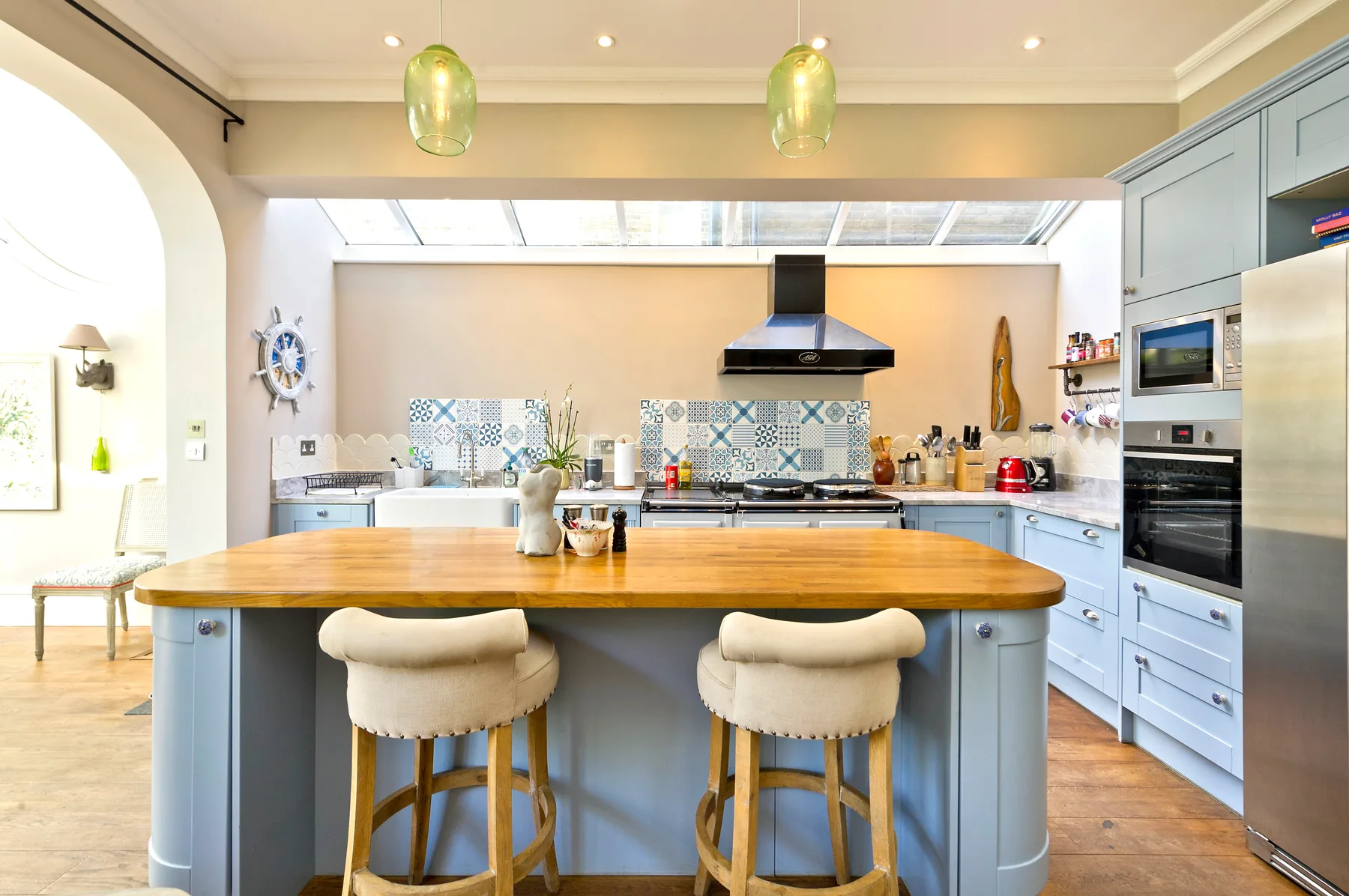 A bright kitchen with a large wooden island and pendant lights.