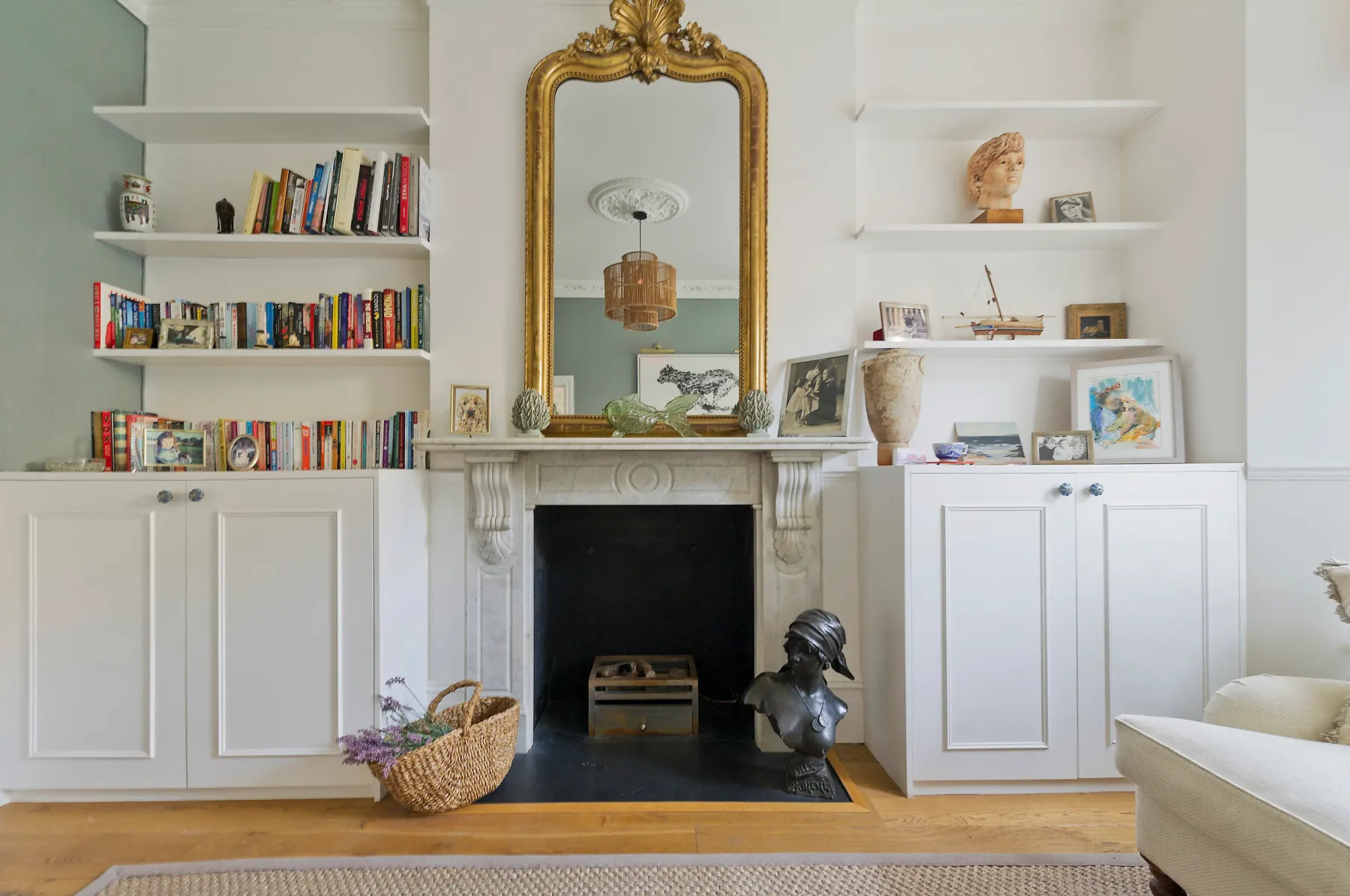 A bright living room with a fireplace, built-in shelves, and a large mirror.