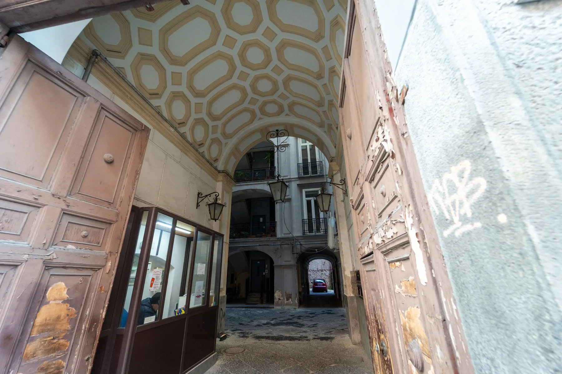 Un pasaje abovedado da a un patio interior con ventanas y puertas.