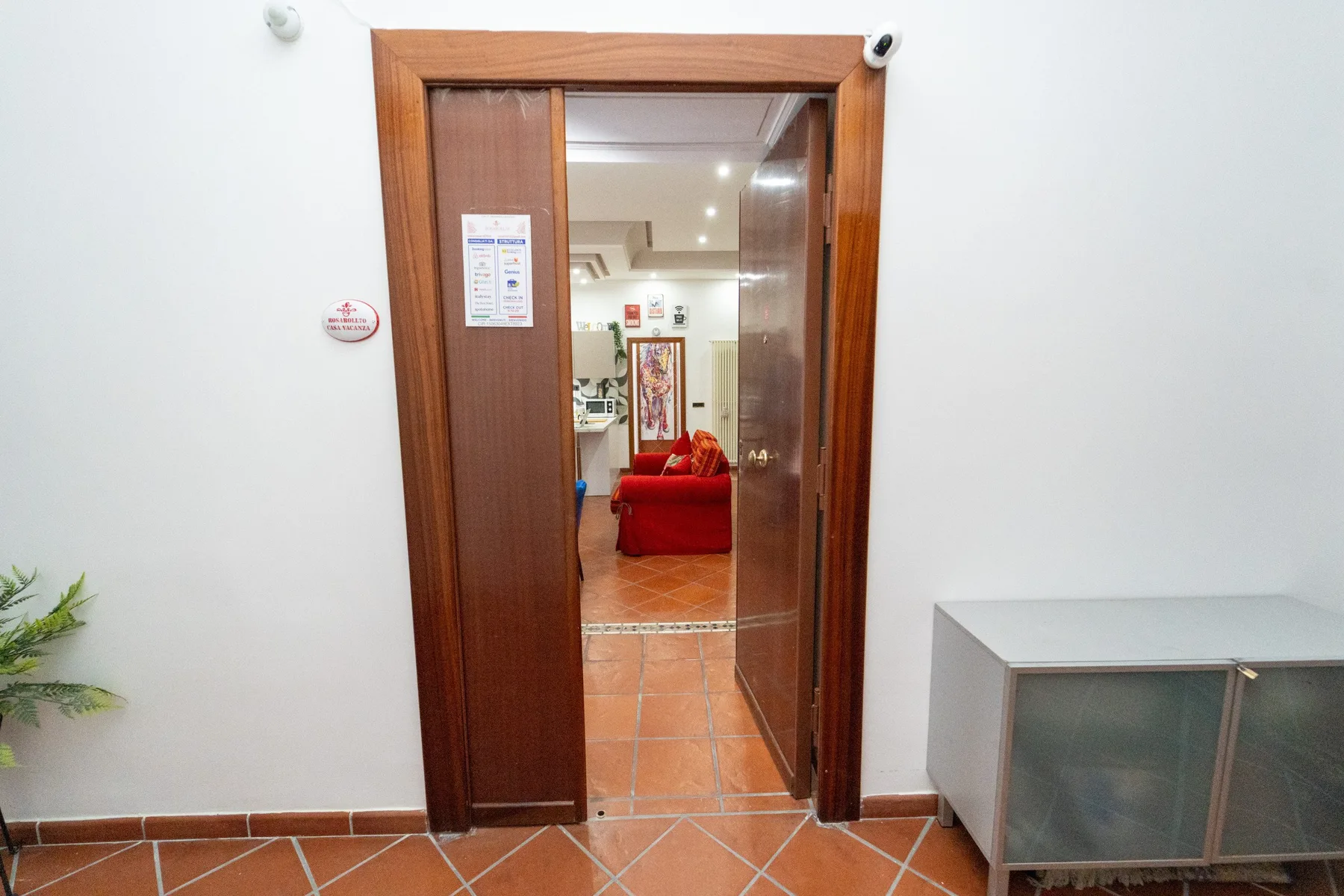 Una puerta abierta da a una habitación con asientos rojos y baldosas de terracota.