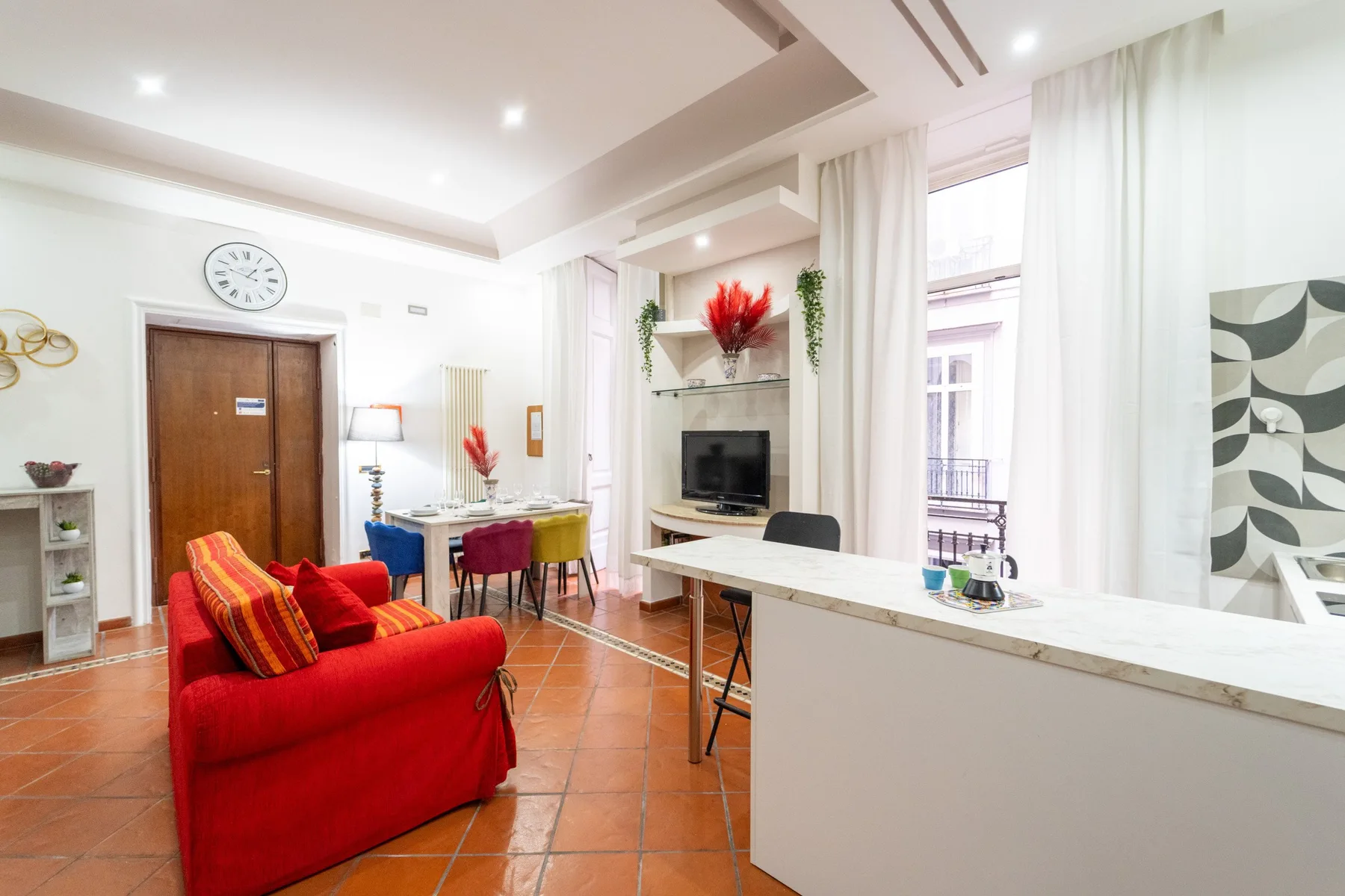 Una luminosa sala de estar y comedor con asientos rojos y una mesa de comedor.