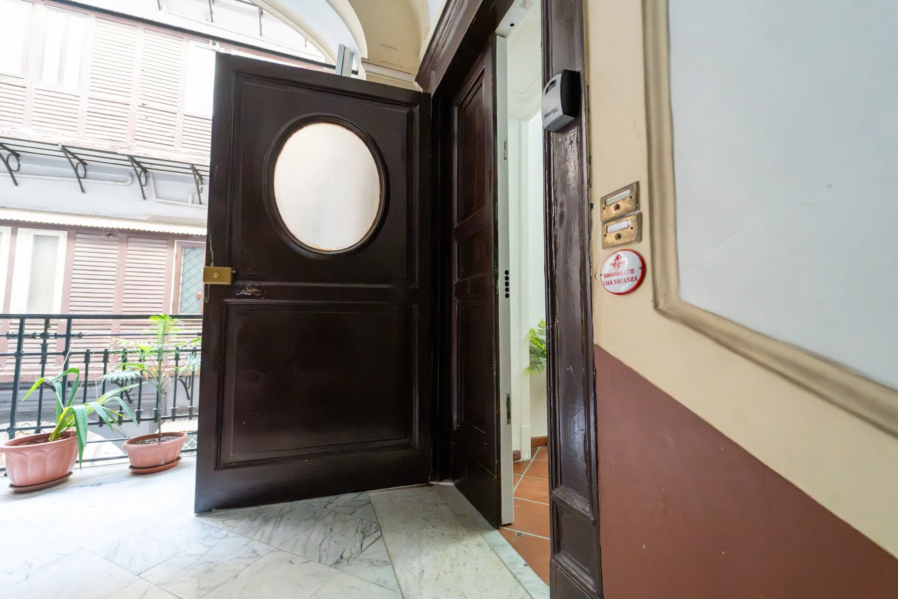 Una puerta abierta da paso a una entrada luminosa con suelo de baldosas.