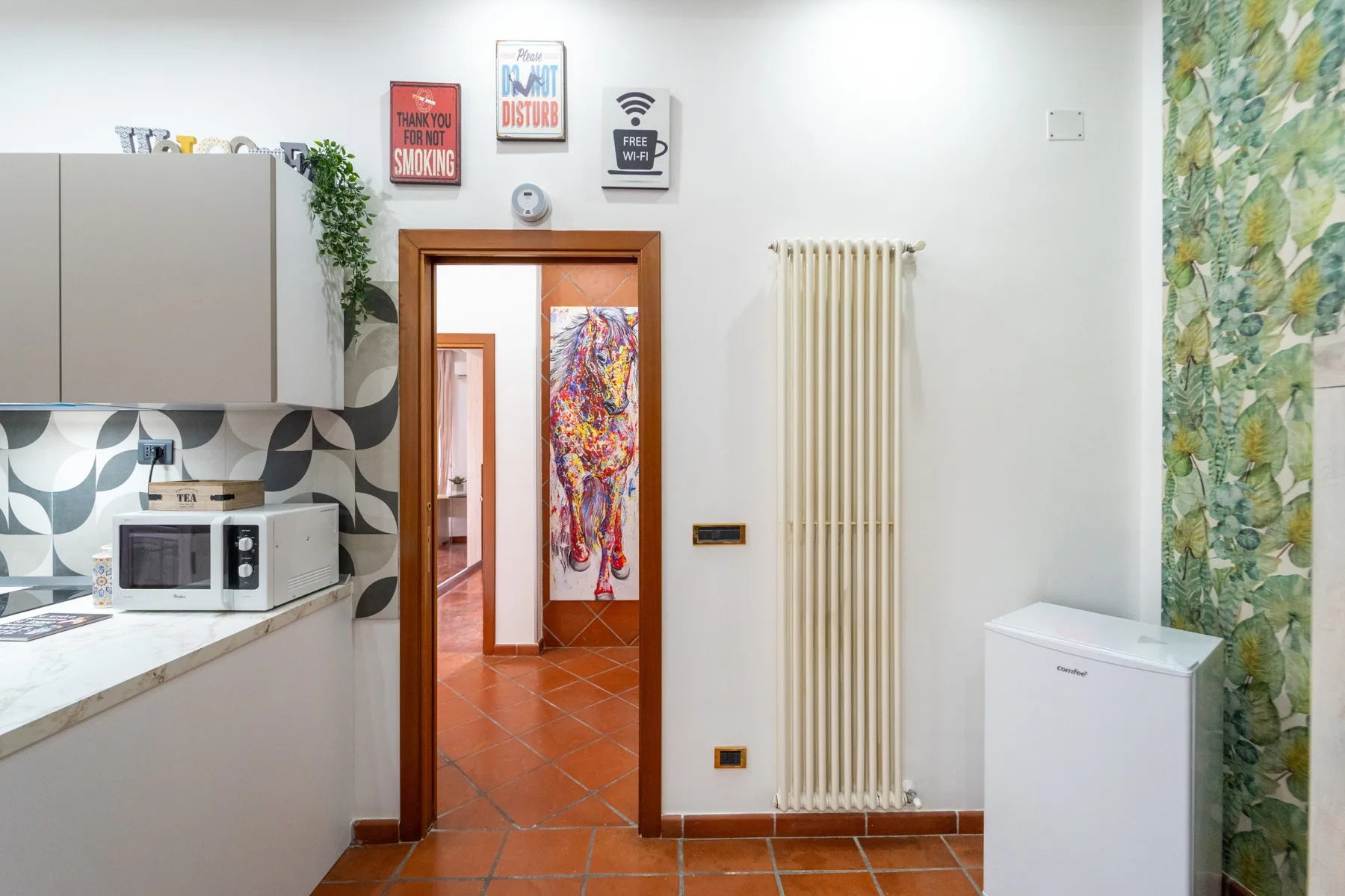 Una cocina da a un pasillo de baldosas con un tapiz colorido.