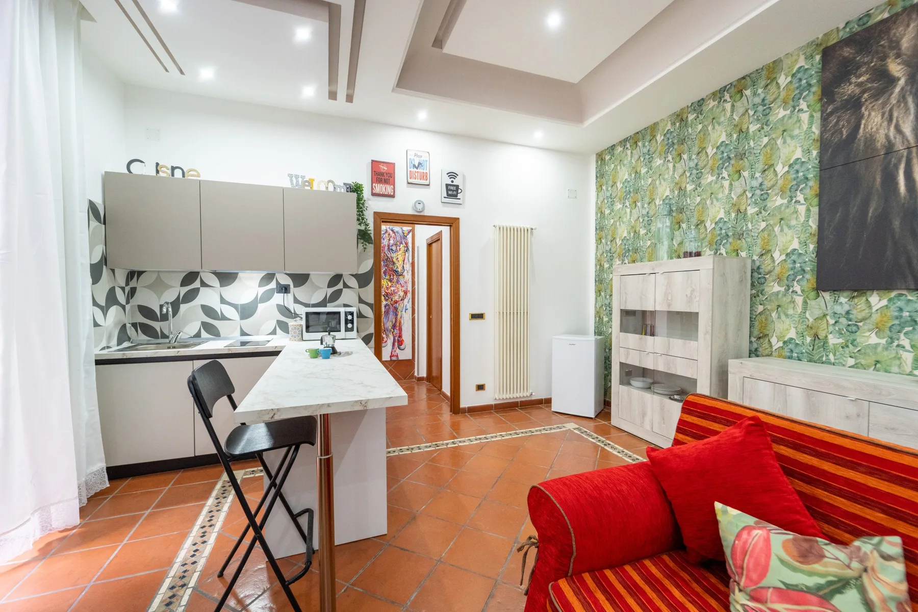 Una sala luminosa con un sofá rojo junto a una cocina abierta.
