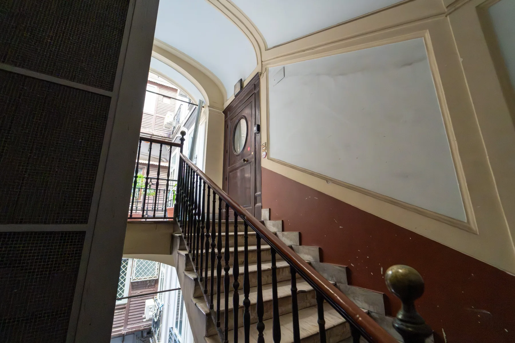 Una escalera interior con pasamanos de madera y grandes paneles en la pared.