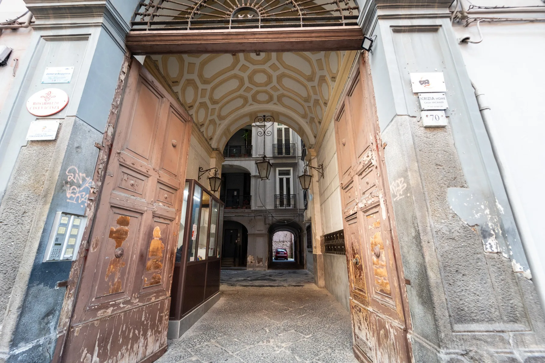 Una entrada con arco da paso a un pasaje con grandes puertas de madera.