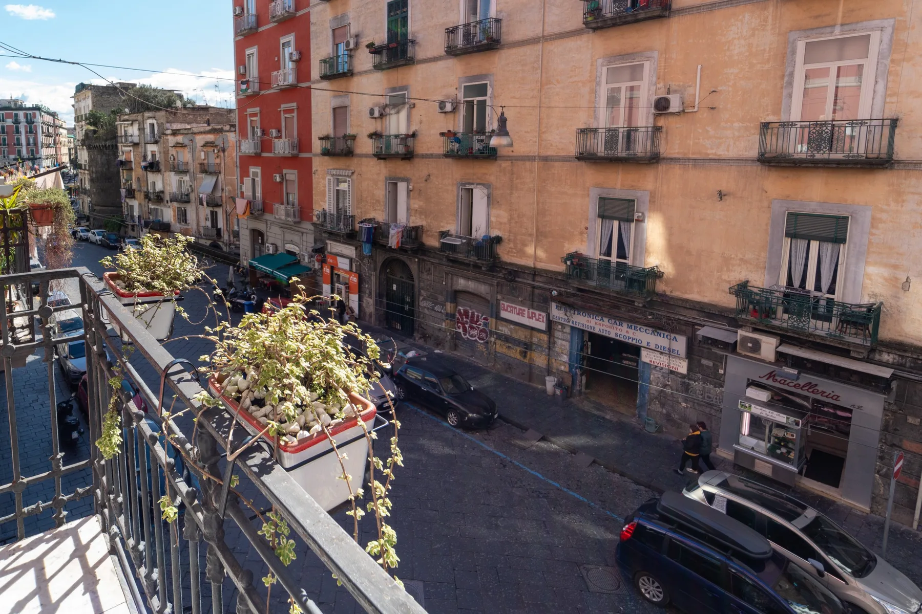 Un balcón da a una calle urbana rodeada de edificios de varios pisos.