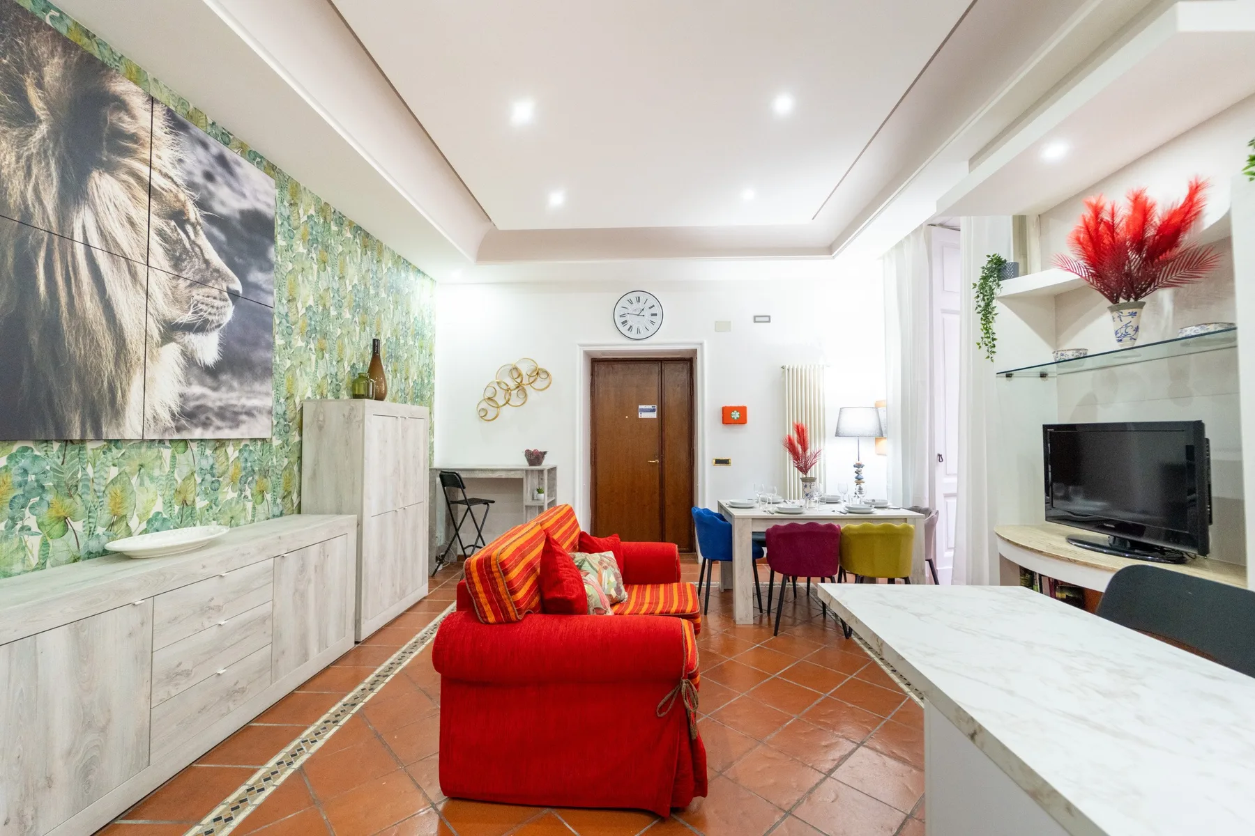 Una sala luminosa con asientos rojos, un televisor y suelo de baldosas.