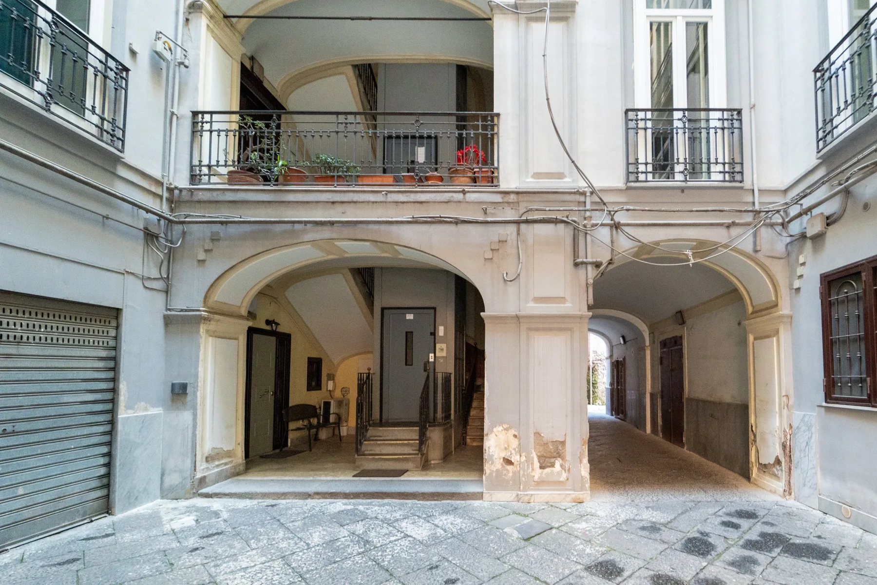 Un pasaje de patio con arcos pasa junto a una entrada retranqueada.