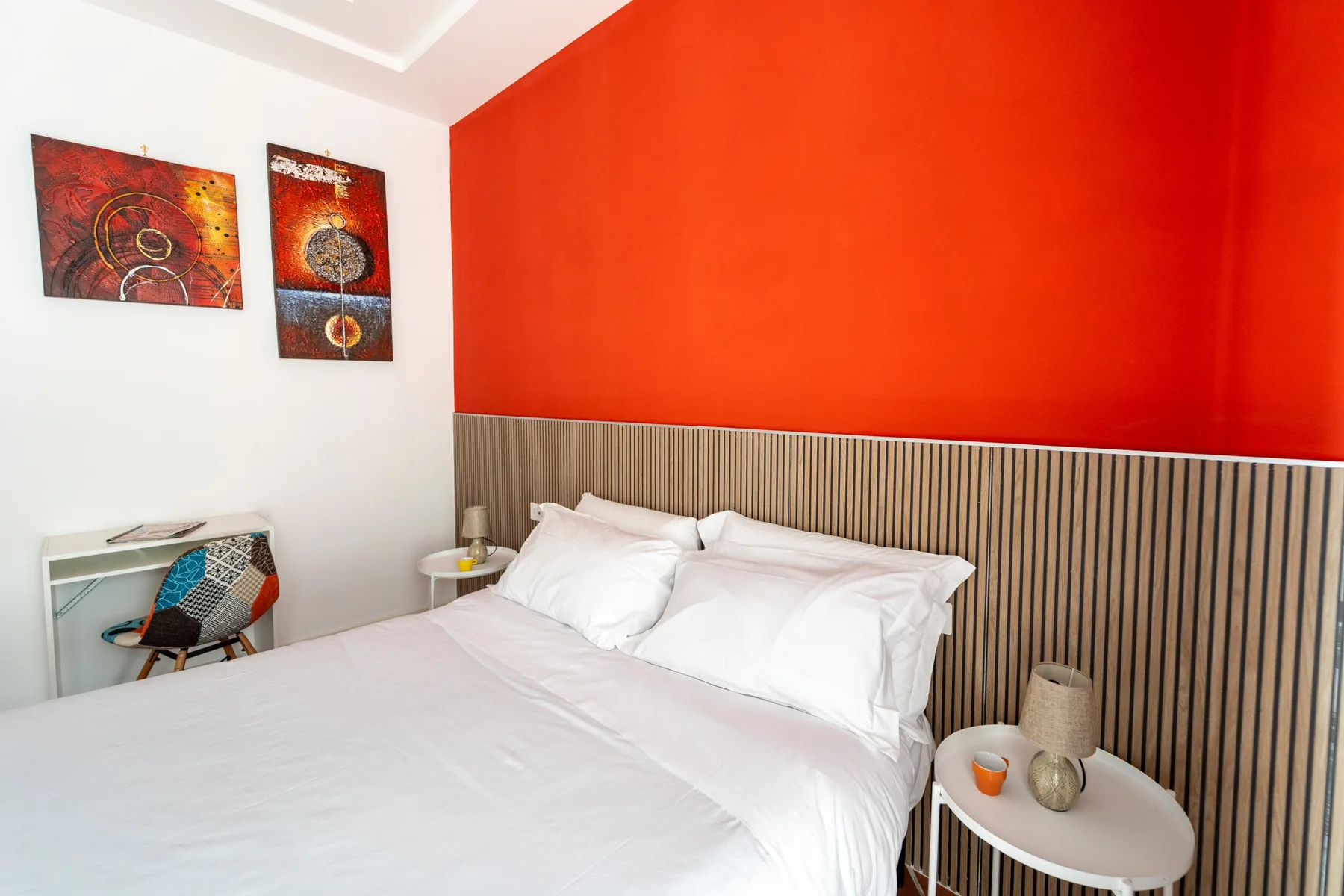 Un dormitorio con una cama blanca y una pared de acento roja.