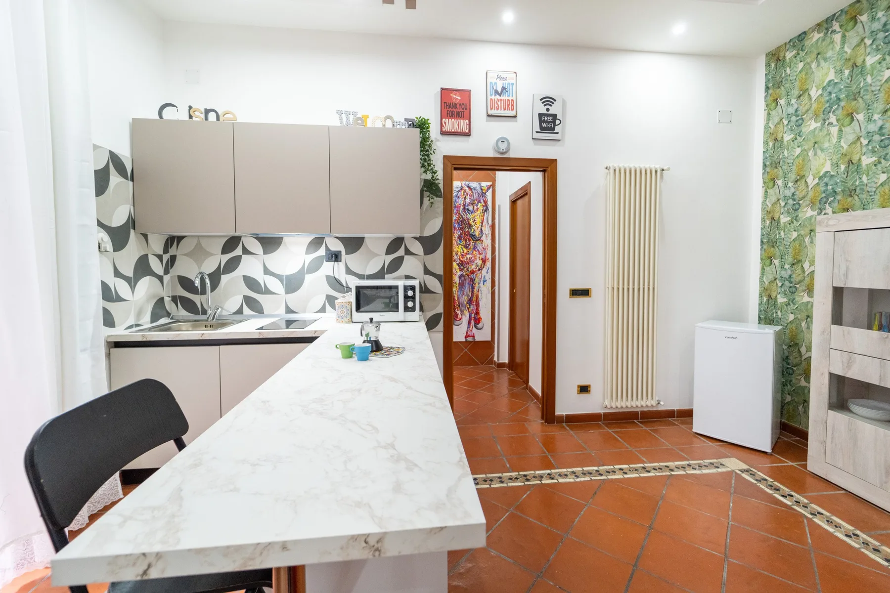 Una cocina luminosa con una encimera larga, un salpicadero estampado y suelo de baldosas.