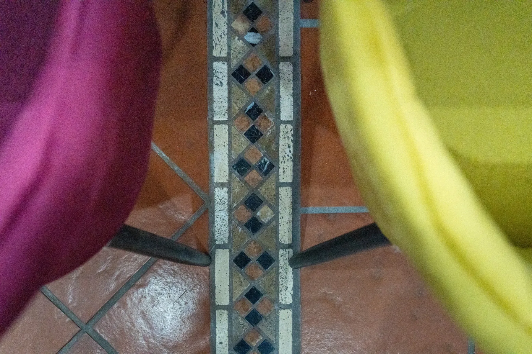 Un suelo de baldosas con una franja decorativa estampada entre asientos de colores.