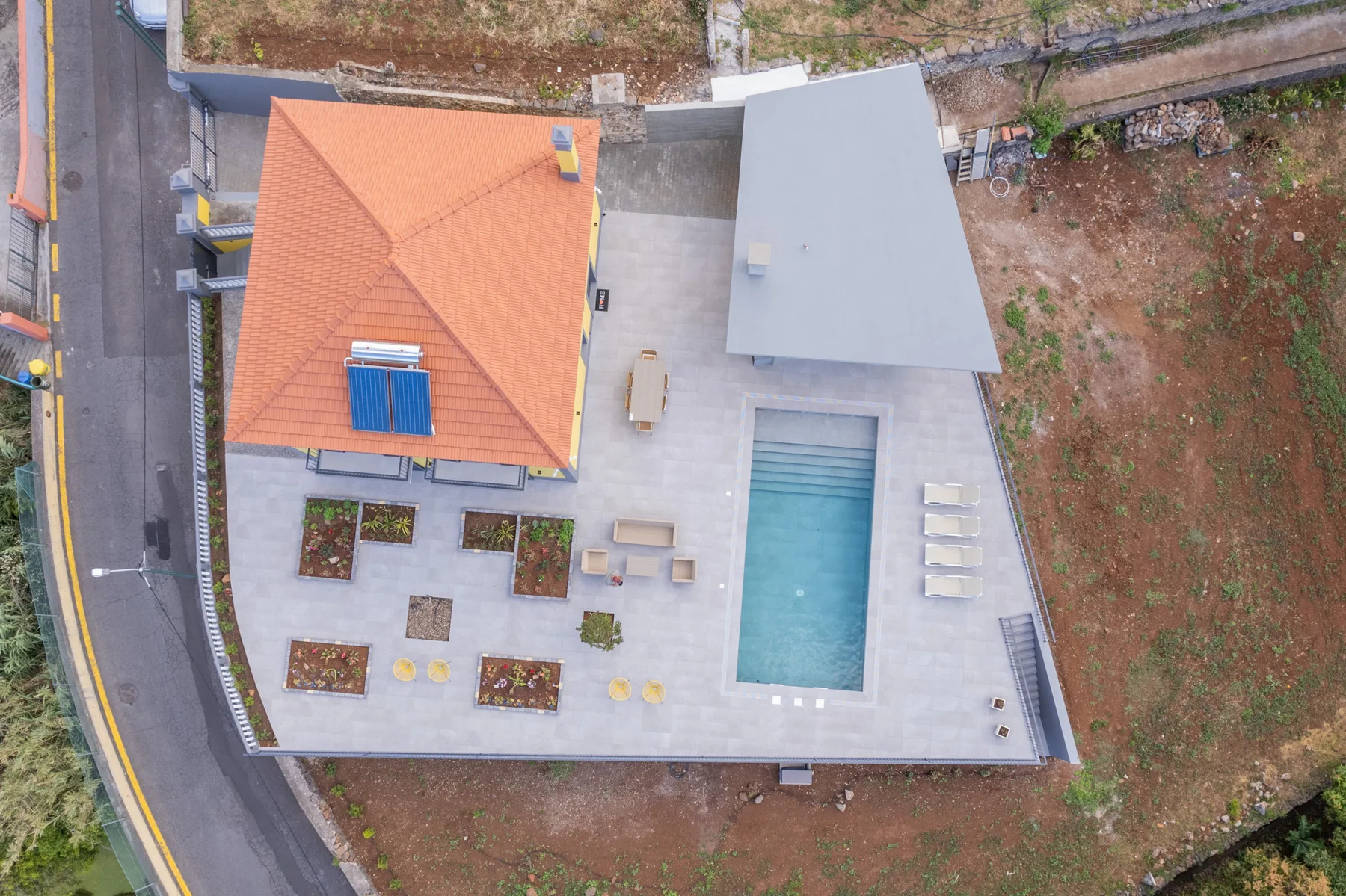 Vista aérea de un patio con piscina y una terraza pavimentada.
