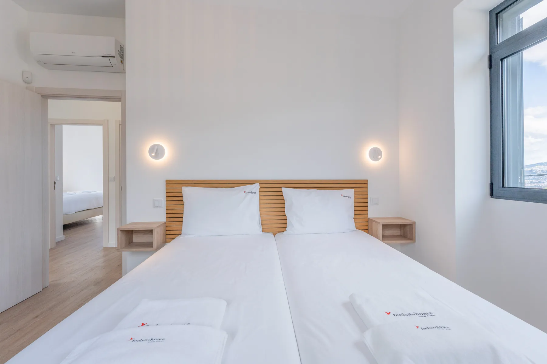 Un dormitorio luminoso con dos camas y una ventana grande.