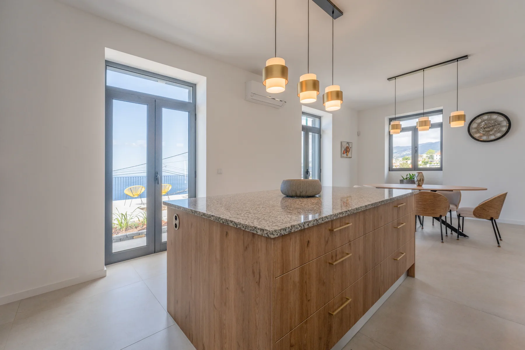 Una cocina luminosa con isla de frente de madera y zona de comedor.