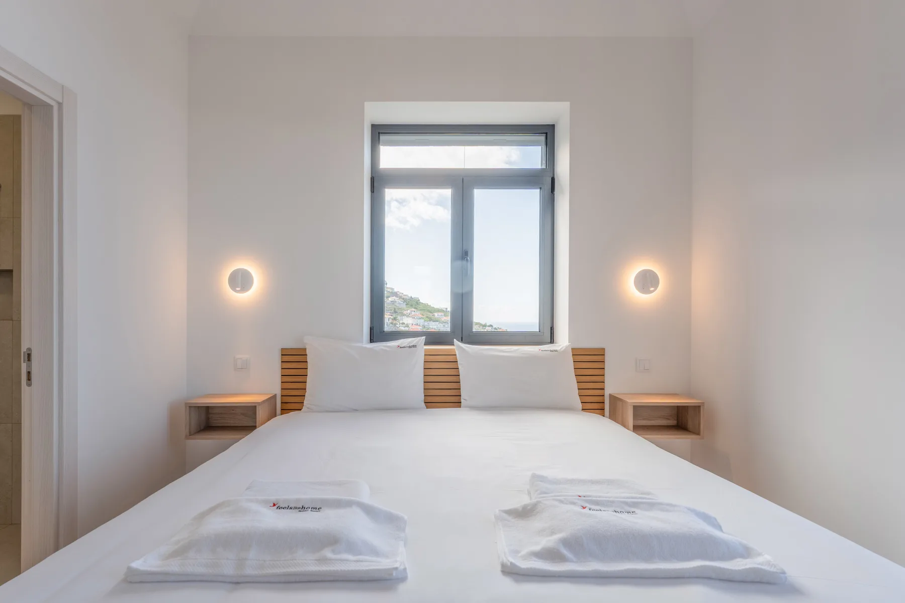 Un dormitorio luminoso con una cama bien hecha y una ventana con vistas al paisaje.