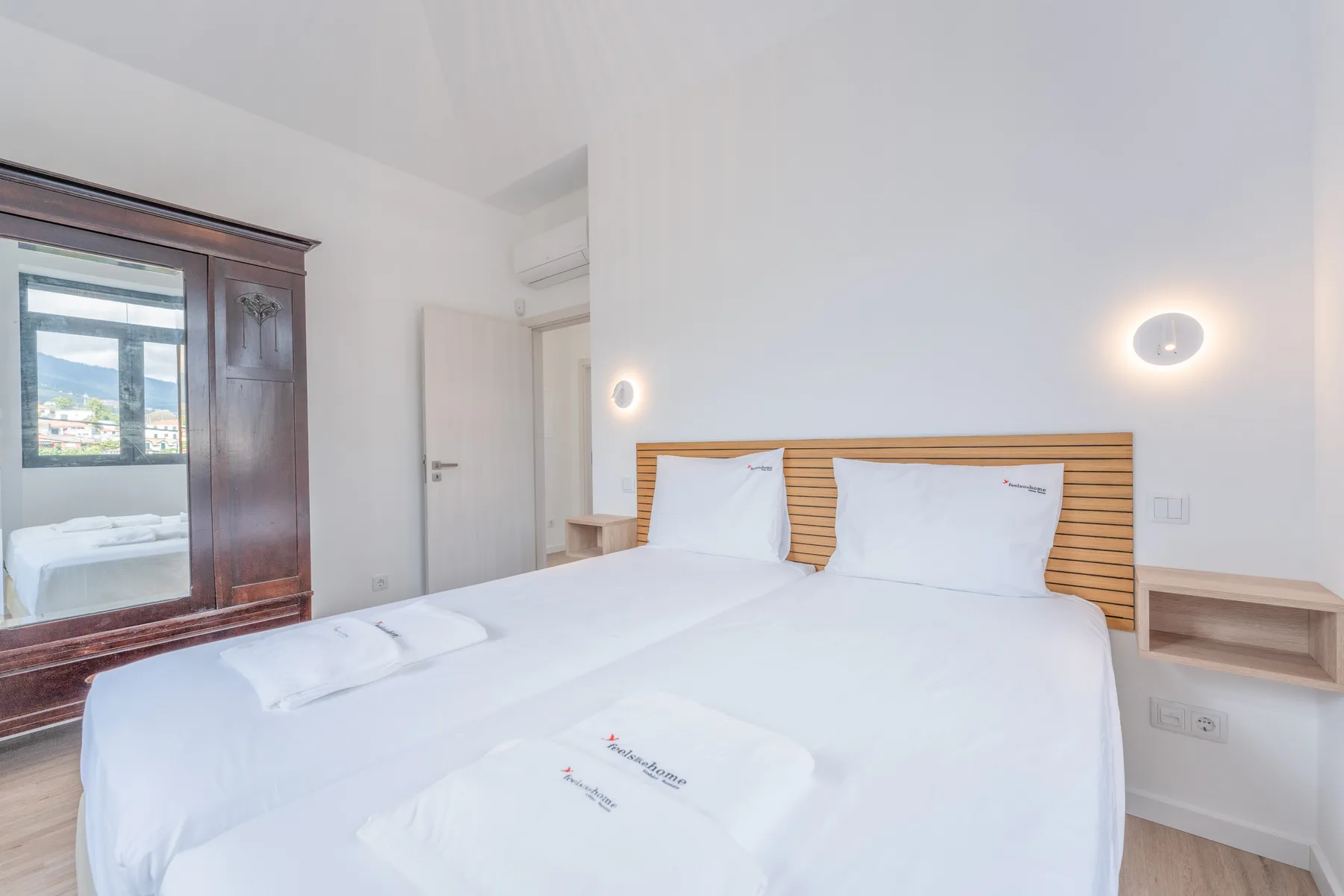 Un dormitorio luminoso con ropa de cama blanca y un cabecero de madera.