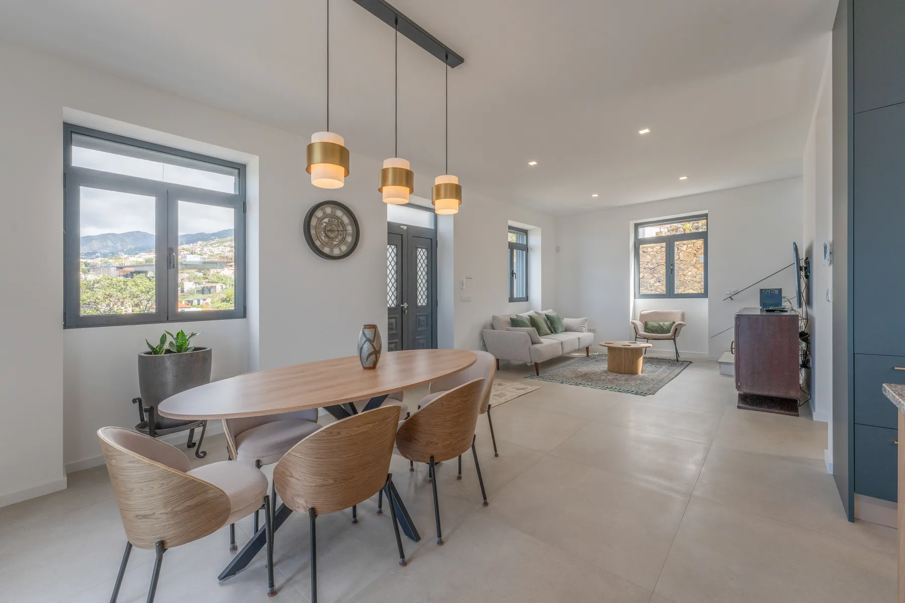 Un espacio abierto de comedor y sala cuenta con una mesa de madera y asientos.