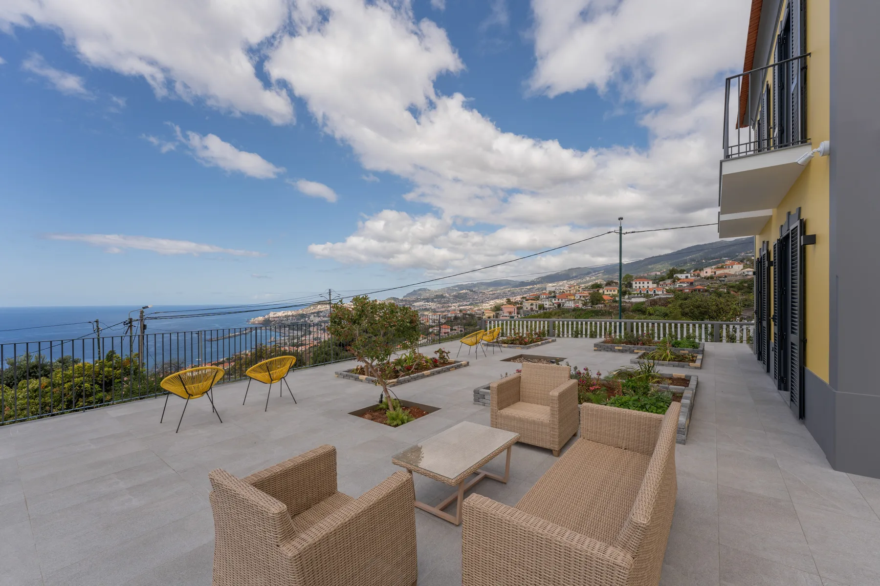 Una terraza pavimentada con asientos al aire libre ofrece vistas al mar y a las colinas costeras.