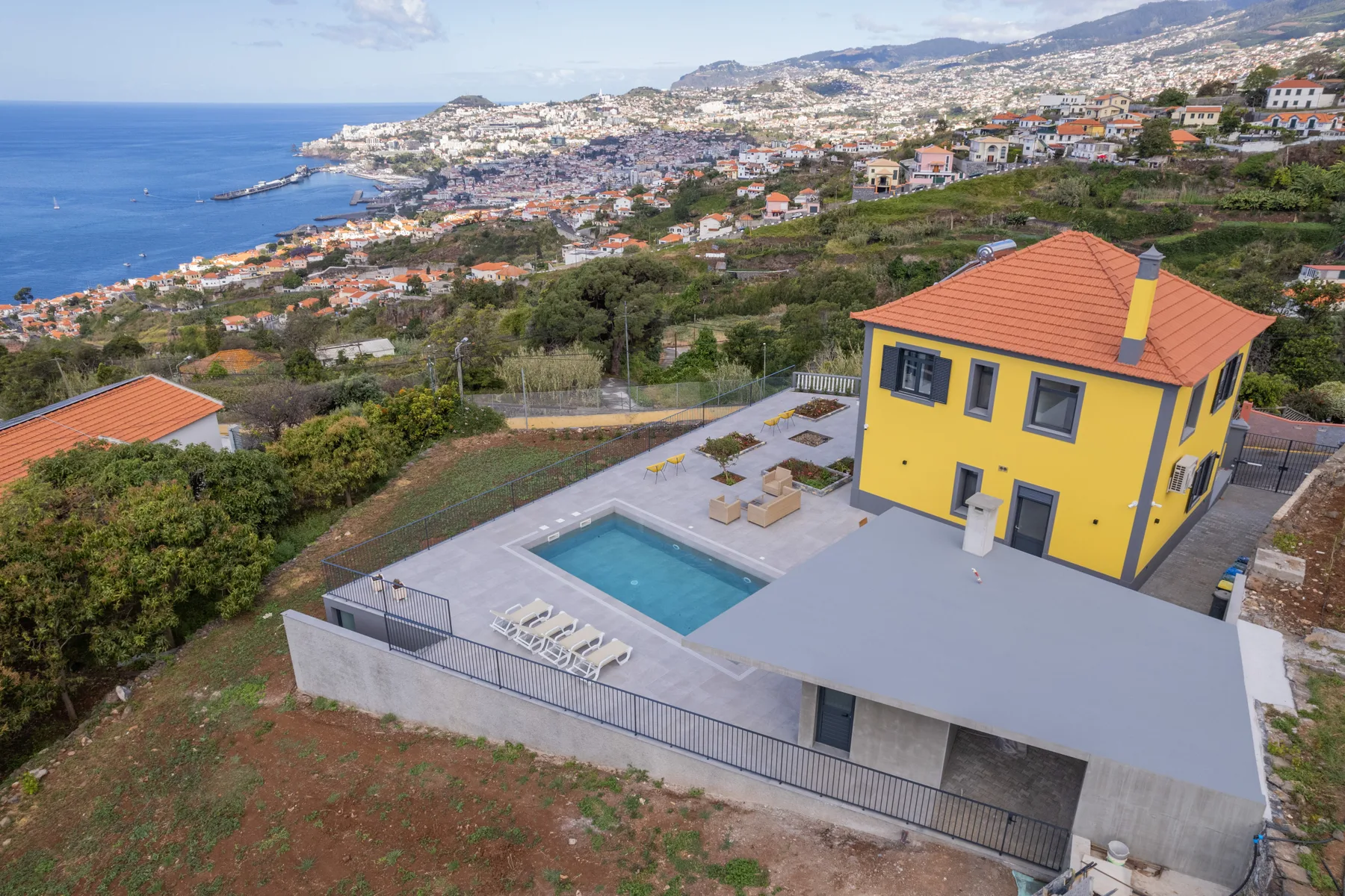 Una casa amarilla da a una piscina y al mar.