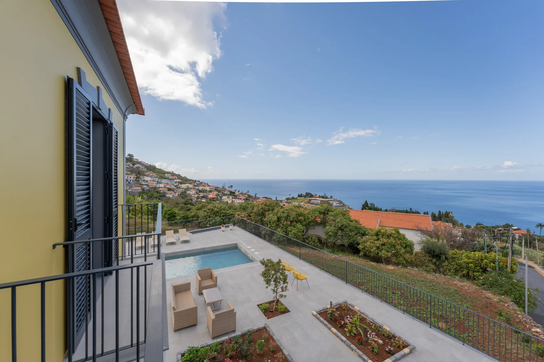 A hillside house overlooks the sea, with a patio and swimming pool.