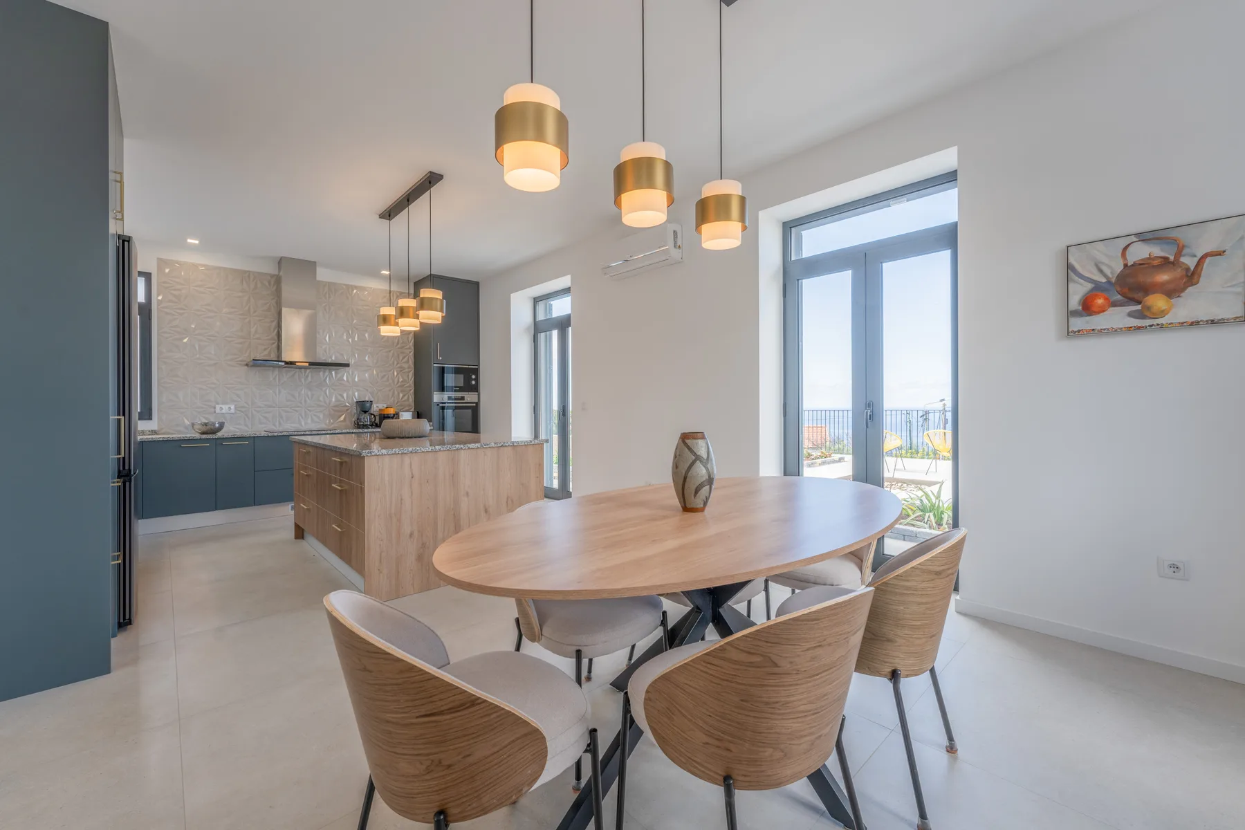 Una cocina abierta con comedor, mesa de madera y lámparas colgantes.
