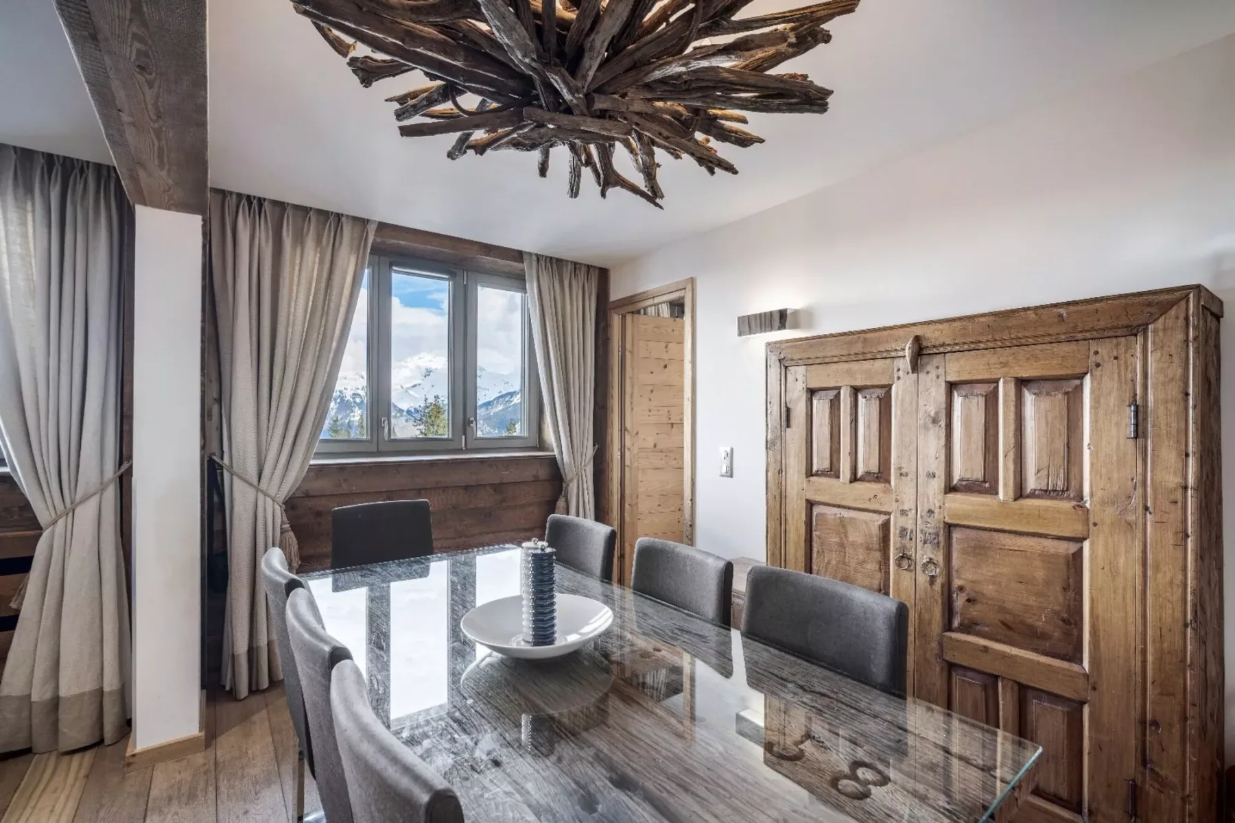 A dining area with a glass table and rustic wooden doors.