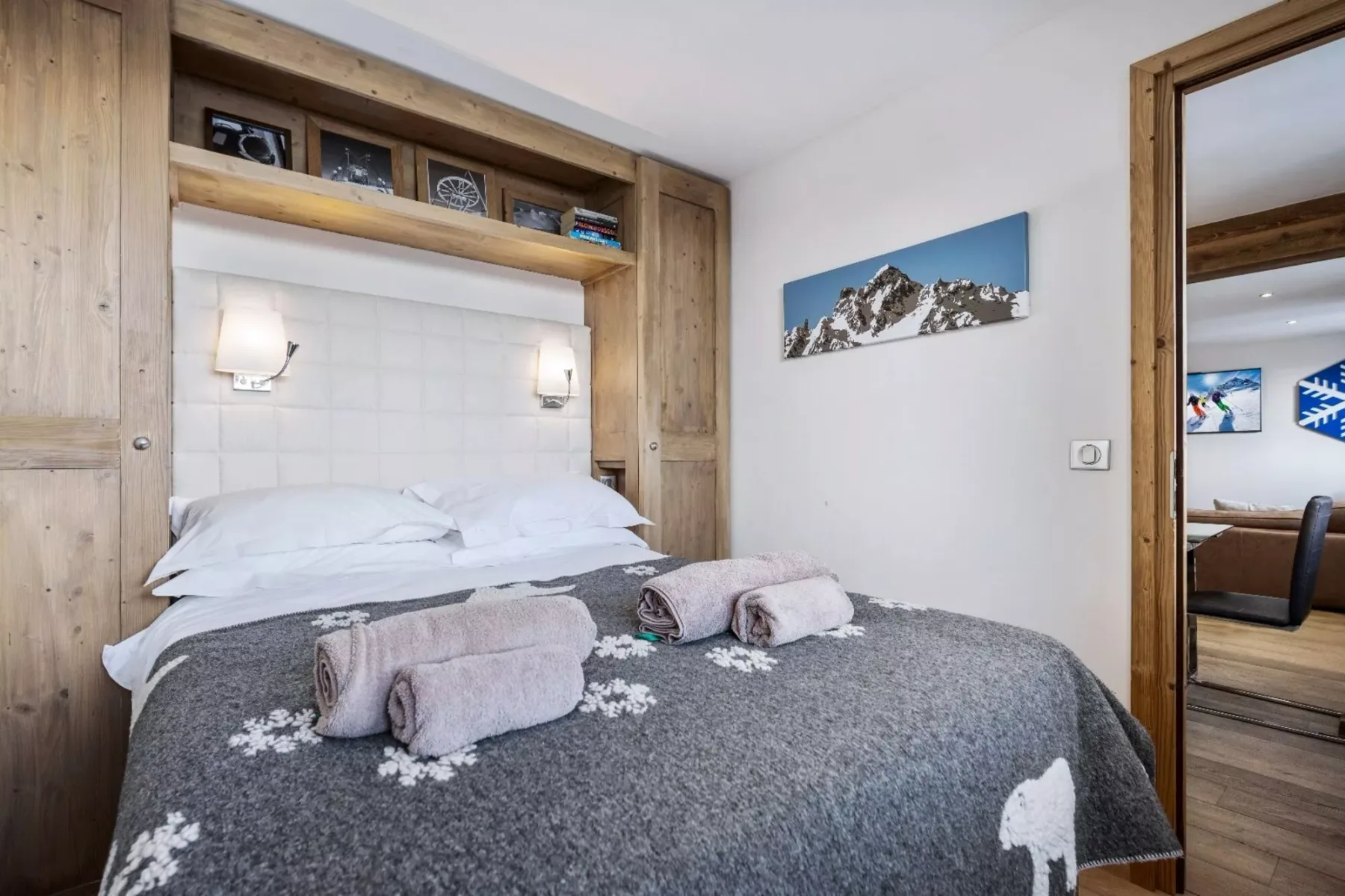 A bedroom with a bed covered by a gray blanket and folded towels.